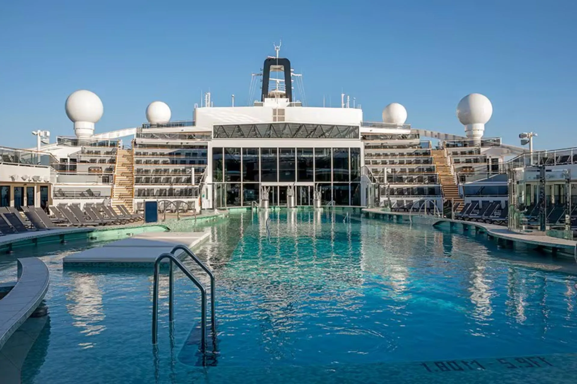 Zwembad op het dek van een MSC Cruise, omgeven door ligstoelen en met uitzicht op de oceaan.