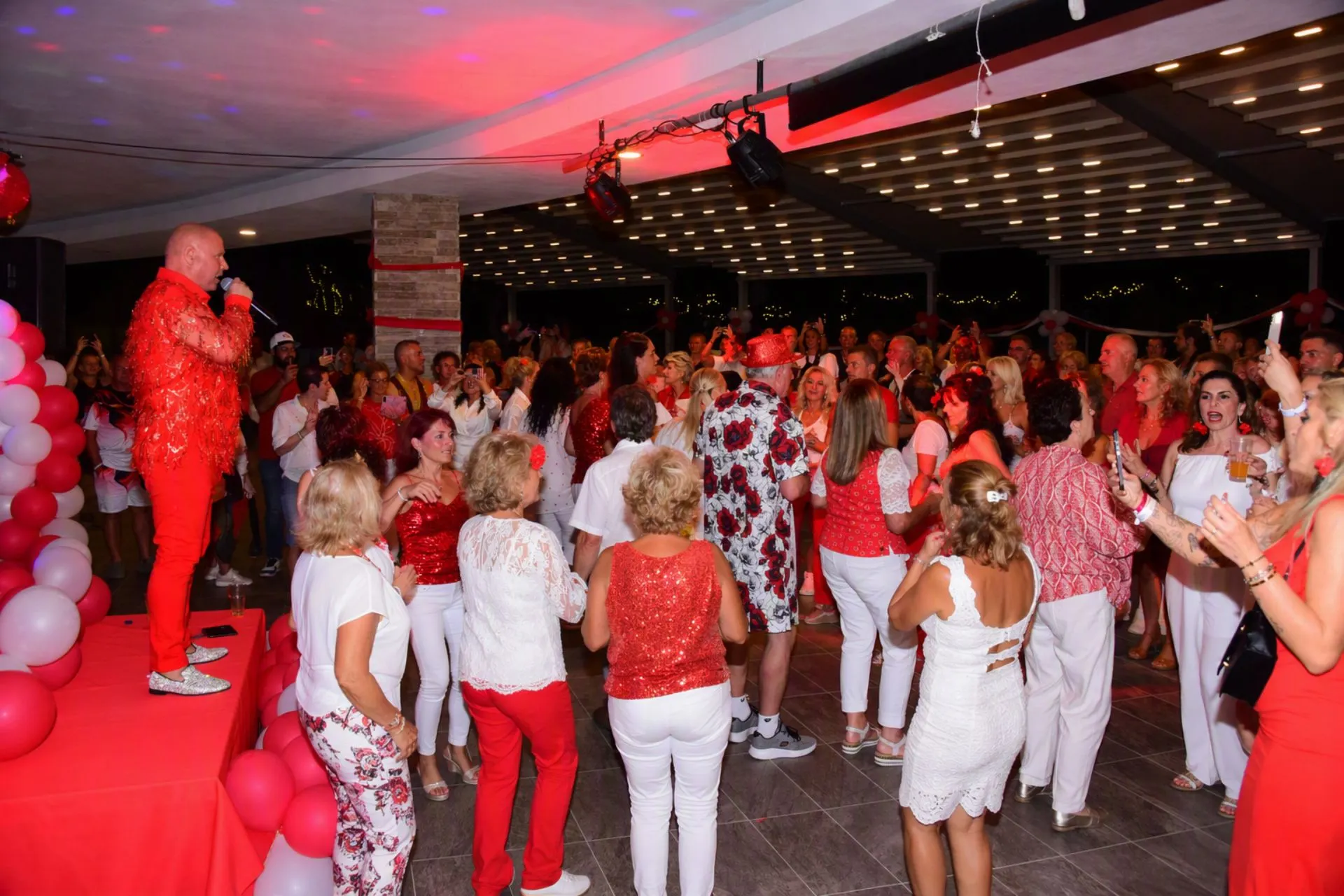 Feestelijke avond in Sunmelia Beach Resort waarbij reizigers genieten van livemuziek, dans en entertainment. Het podium, de rood-witte decoratie en de volle dansvloer zorgen voor een gezellige sfeer. Avondactiviteiten zoals deze vormen een van de hoogtepunten van een artiestenreis naar Turkije.

