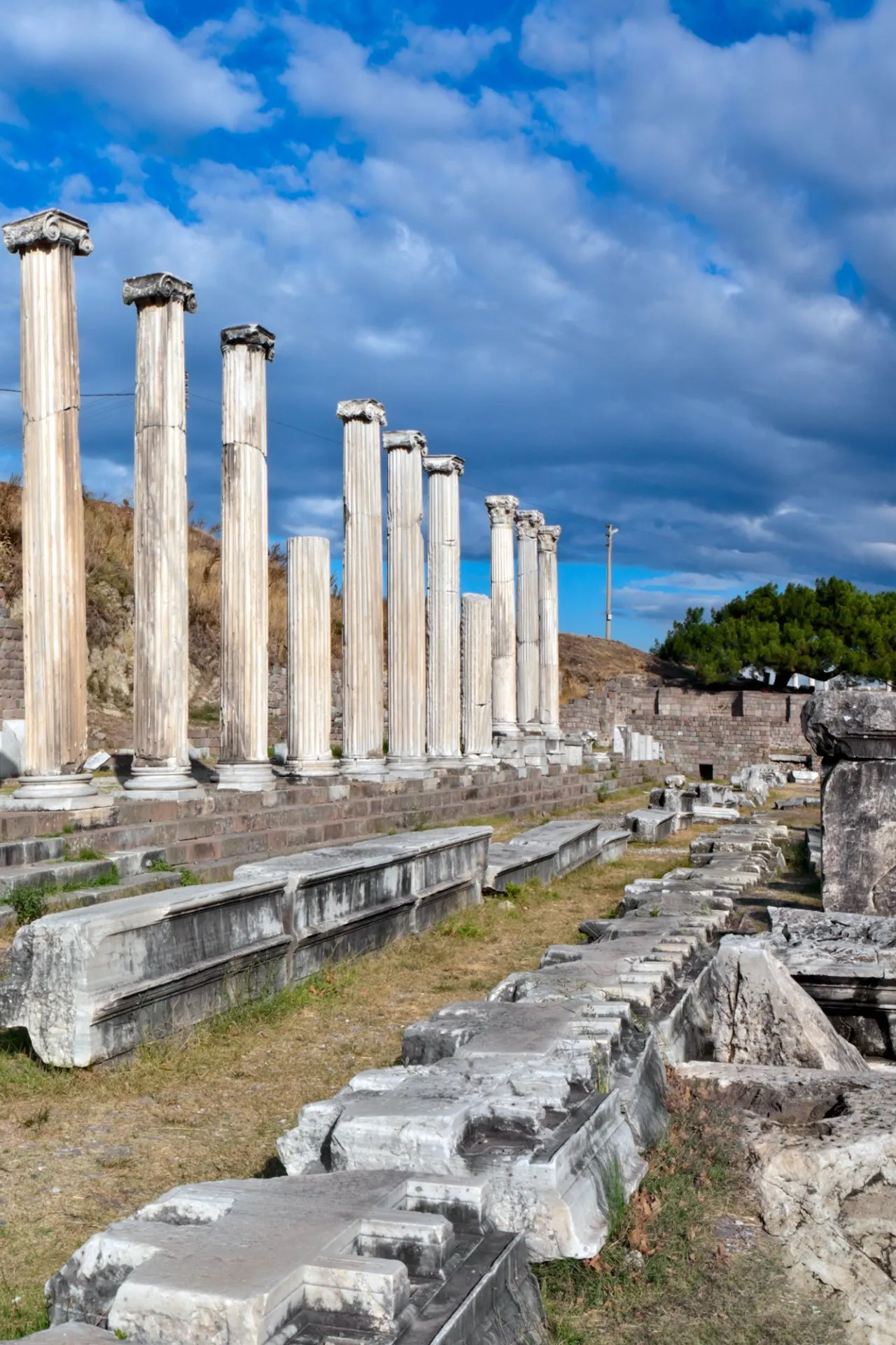 Rijtje goed bewaarde antieke zuilen bij het Asklepion op Kos, een historisch Grieks heiligdom met resten van oude tempelmuren en stenen blokken onder een blauwe lucht