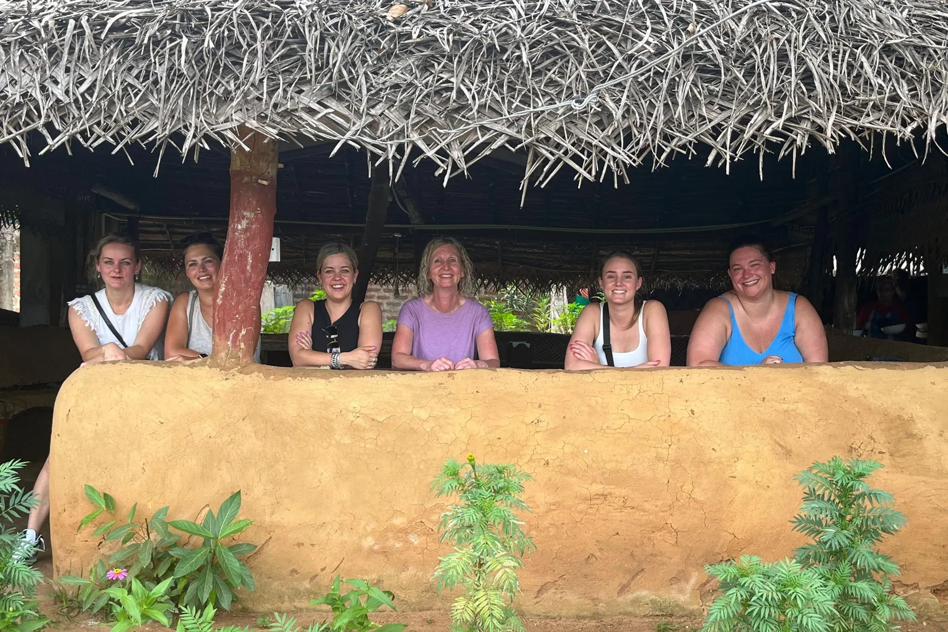 Groep vrouwen poseert onder een rieten dak in een traditioneel restaurant in Sri Lanka.

