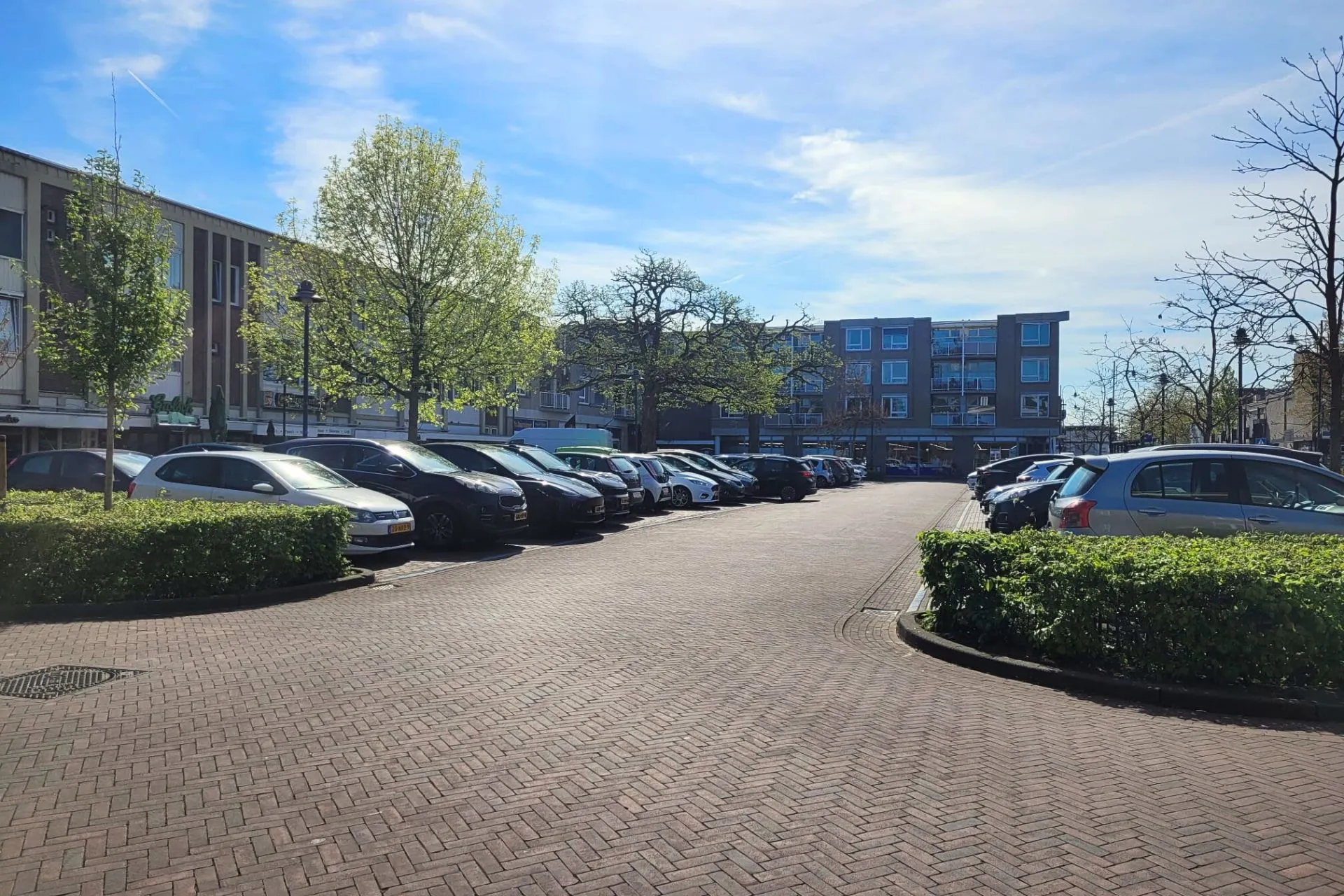  Parkeerplaats bij de Action in Veghel op een zonnige dag met blauwe lucht; een rij met parkeerplaatsen waar je 2 uur mag parkeren met een blauwe schijf. Vanaf hier is het 3 minuten lopen naar Travelcenter de Wit Veghel.