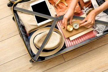 Ingepakte koffer met kleding, schoenen en reisbenodigdheden, klaar voor vertrek.