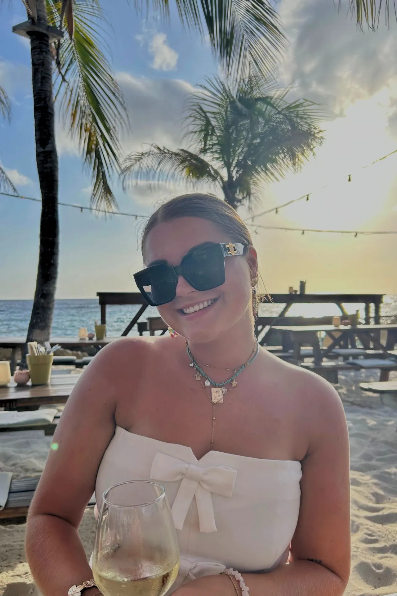 Lara van Cuijk aan het dineren op het strand Curaçao met palmbomen en zeezicht