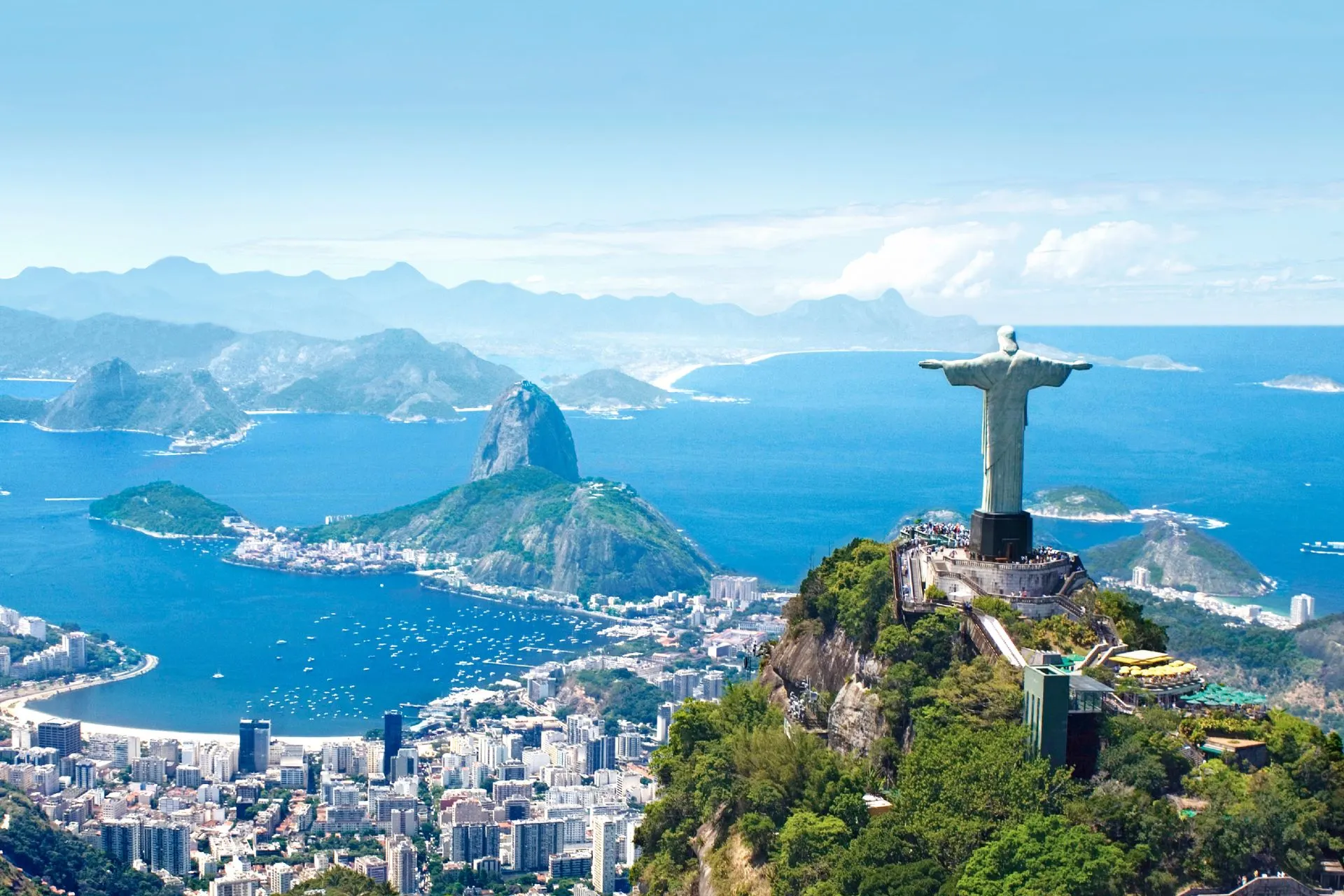 Uitzicht op Rio de Janeiro met het beroemde Christus de Verlosser-beeld op de voorgrond, uitkijkend over de baai van Guanabara en de Suikerbroodberg.