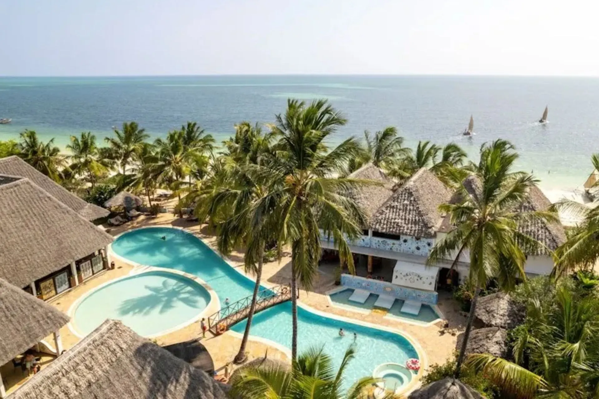 Overzicht van Jaz Adonia Beach Resort in Uroa Beach op Zanzibar. Het resort ligt direct aan het strand en beschikt over meerdere zwembaden, tropische palmbomen en gebouwen in Afrikaanse stijl met rieten daken. Vanuit het resort geniet je van uitzicht op de turquoise Indische Oceaan en de ontspannen sfeer van de oostkust van Zanzibar.