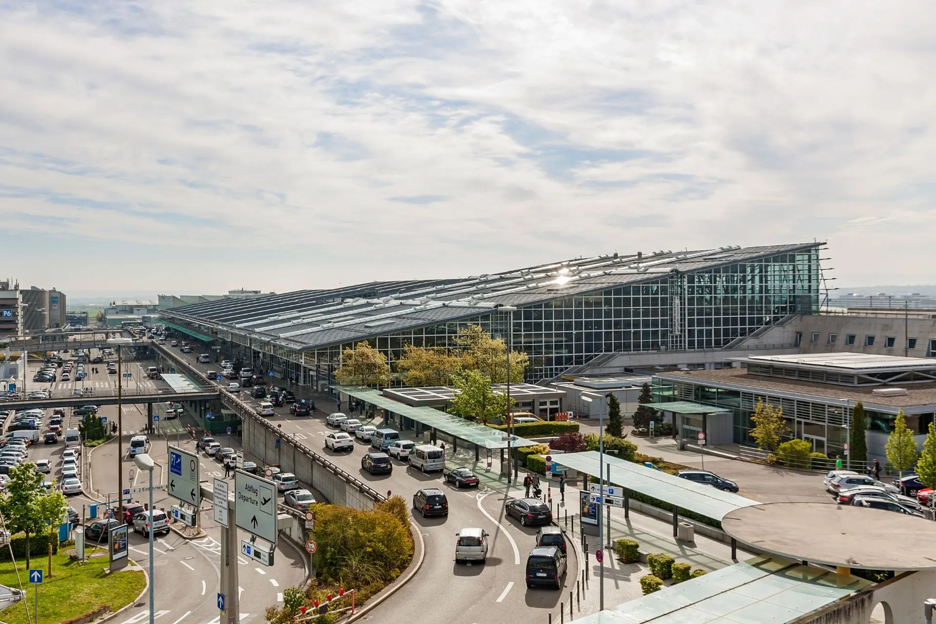 Drukke luchthaven Münster Osnabrück Airport met auto's en incheckzones. Perfect voor vliegen vanaf Münster en goedkope vluchten naar populaire bestemmingen.