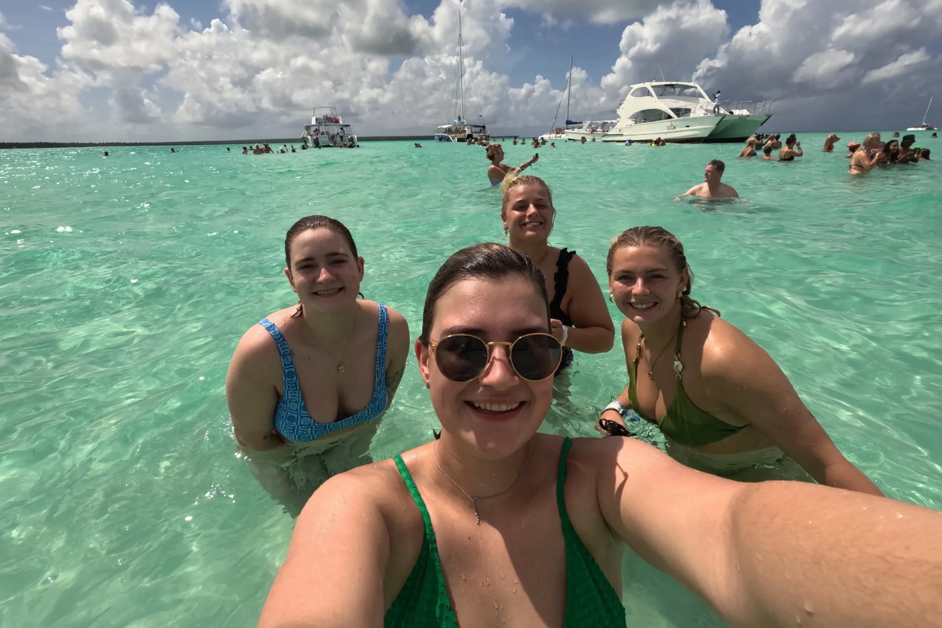 Vier lachende vrouwen genieten samen in het heldere, turquoise water van de Dominicaanse Republiek.
