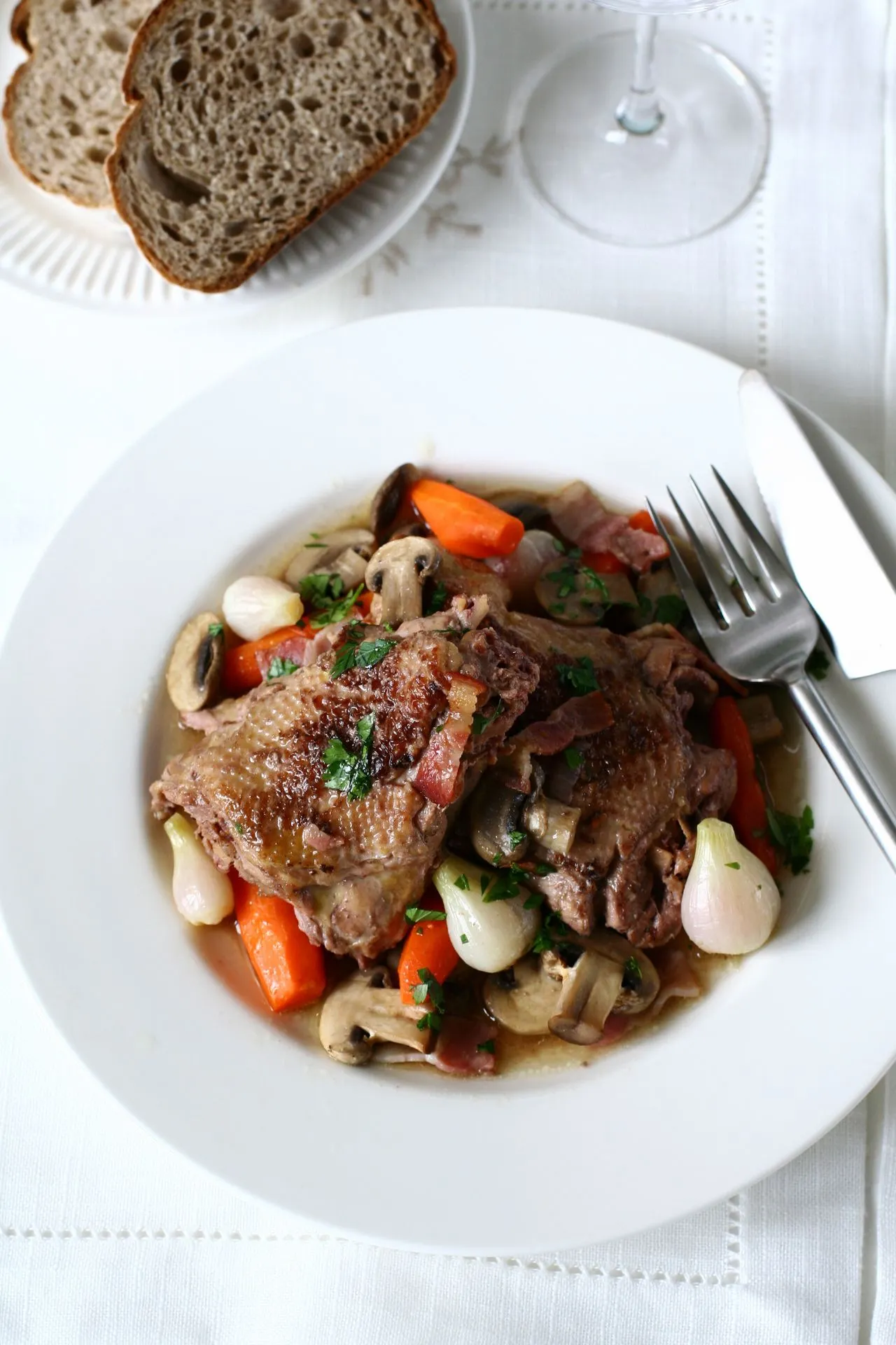 Een bord met coq au vin in Parijs, een klassiek Frans gerecht van langzaam gestoofde kip in een rijke rode wijnsaus, geserveerd met groenten en aardappelen.