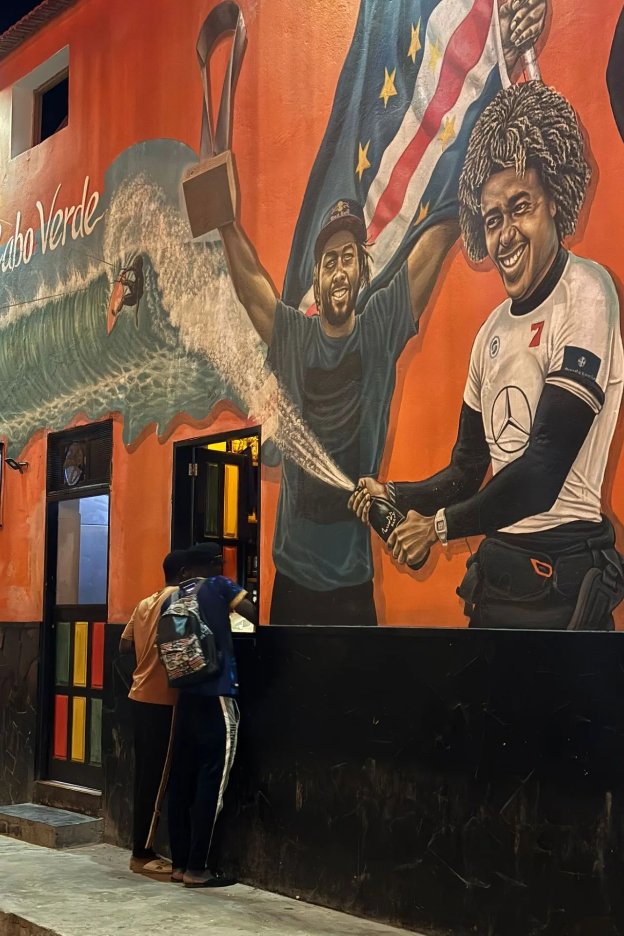 Avondscène in Santa Maria op het eiland Sal, waar een kleurrijke muurschildering met de tekst I love Sal het straatbeeld bepaalt. De combinatie van lokale kunst, verweerde muren en het straatleven geeft een authentieke indruk van Kaapverdië. Dit beeld past goed bij een vakantie Kaapverdië waarin cultuur en dagelijks leven centraal staan. Voor reizigers die meer willen zien dan zon en strand, laat deze plek zien hoe kunst en identiteit samenkomen op het eiland.