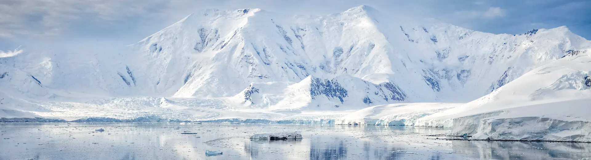 Grote witte berg bedekt met sneeuw en ijs, omringd door helder water in Antarctica.