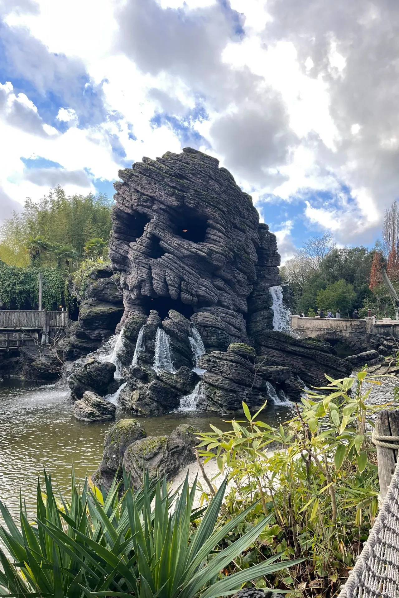 Skull Rock in Adventureland, Disneyland Parijs, een indrukwekkende rotsformatie in de vorm van een schedel met stromend water, omringd door tropische planten. Dit iconische element maakt deel uit van het piratenthema en is een populaire plek voor foto’s en ontdekkingstochten