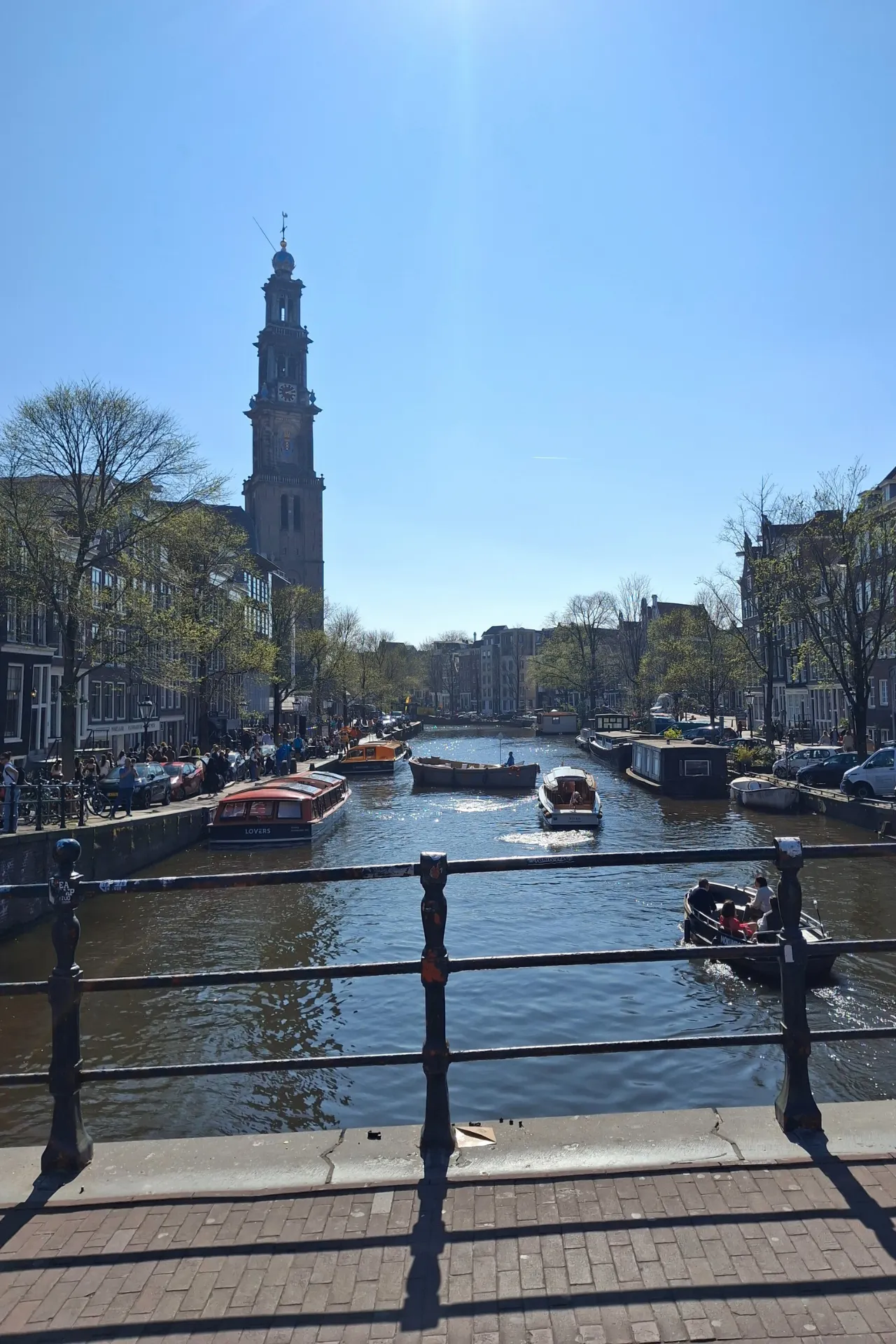 Uitzicht vanaf een brug in Amsterdam op het water met verschillende bootjes die rustig varen.