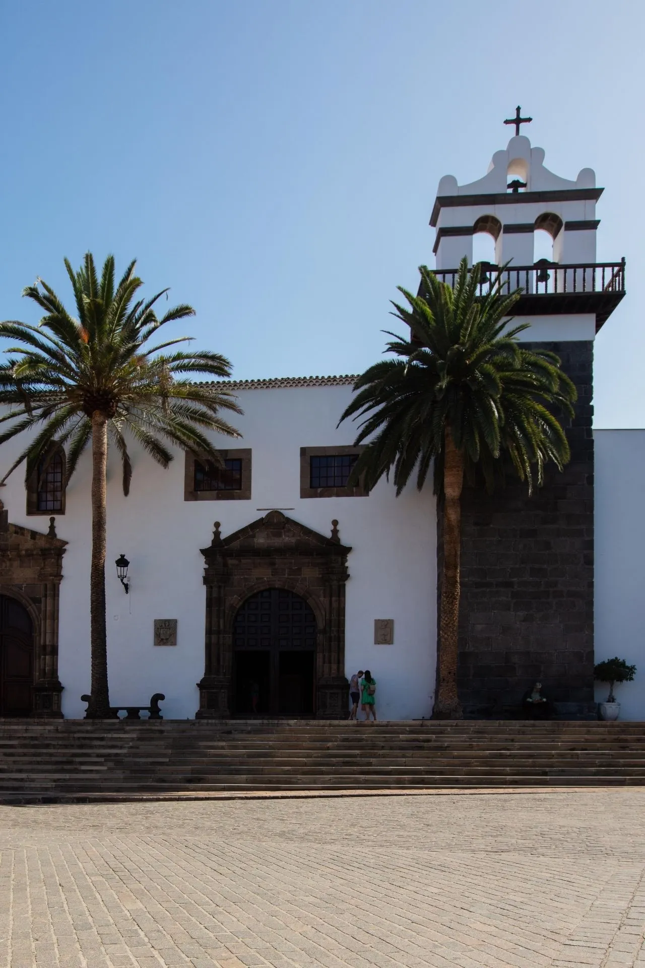 Historische witte kerk met palmbomen aan een plein op Tenerife.