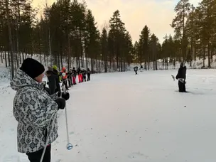 Sneeuwschoen safari in Finland, je ziet een aantal mensen op een rijtje met stokken in de hand.