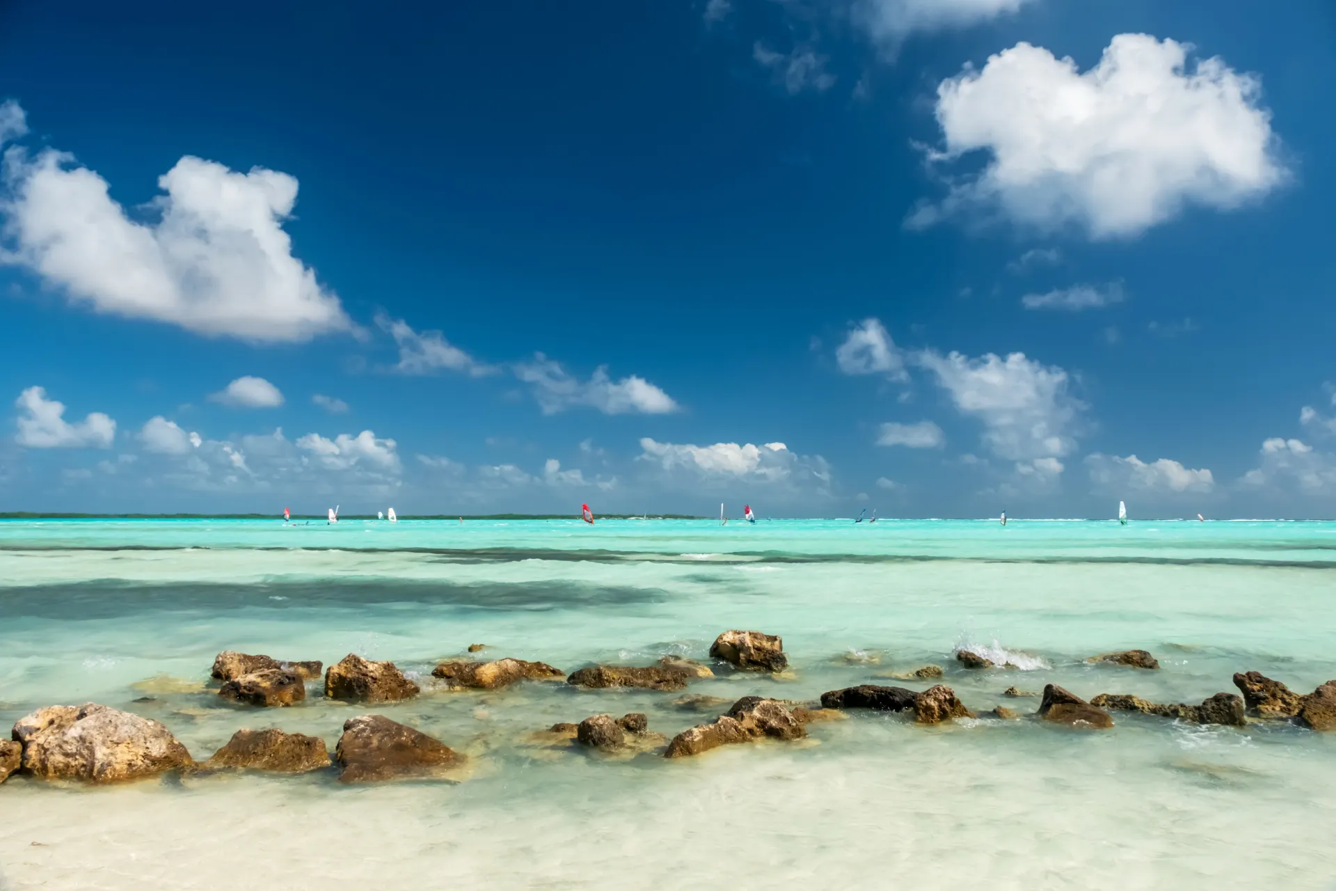 "Paradijselijk strand met turquoise water, rotsen in de branding en een strakblauwe lucht met witte wolken, ideaal voor een zonovergoten vakantie. Kristalheldere zee, natuurlijke schoonheid en afgelegen ligging maken deze bestemming perfect voor ontspanning, zwemmen en fotografie. Ongerepte natuur en authentieke sfeer creëren een paradijs voor reizigers die houden van rust, avontuur en unieke landschappen."
