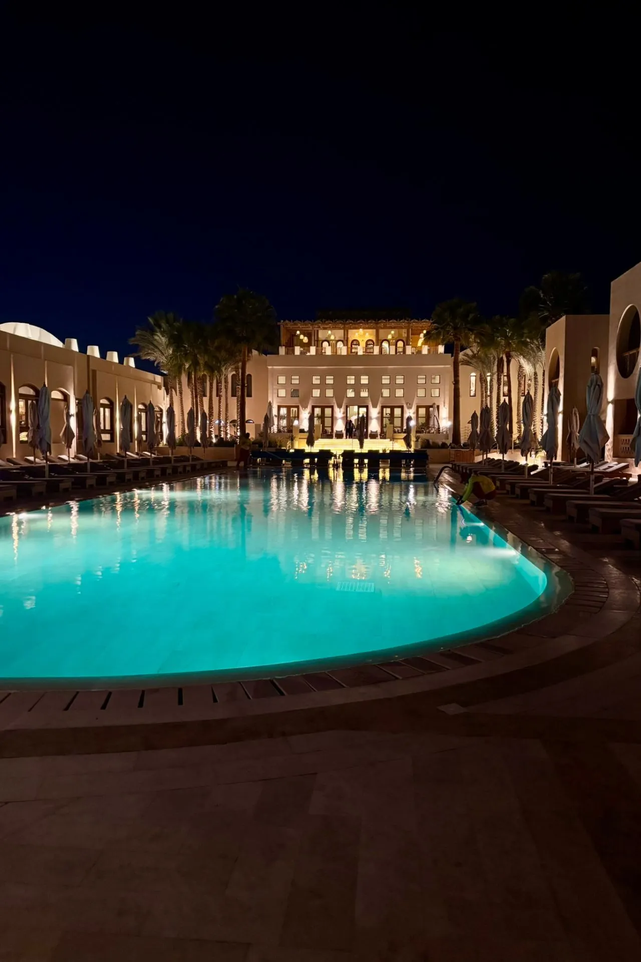 Verlicht zwembad bij een resort in Egypte met palmbomen en sfeervolle avondverlichting