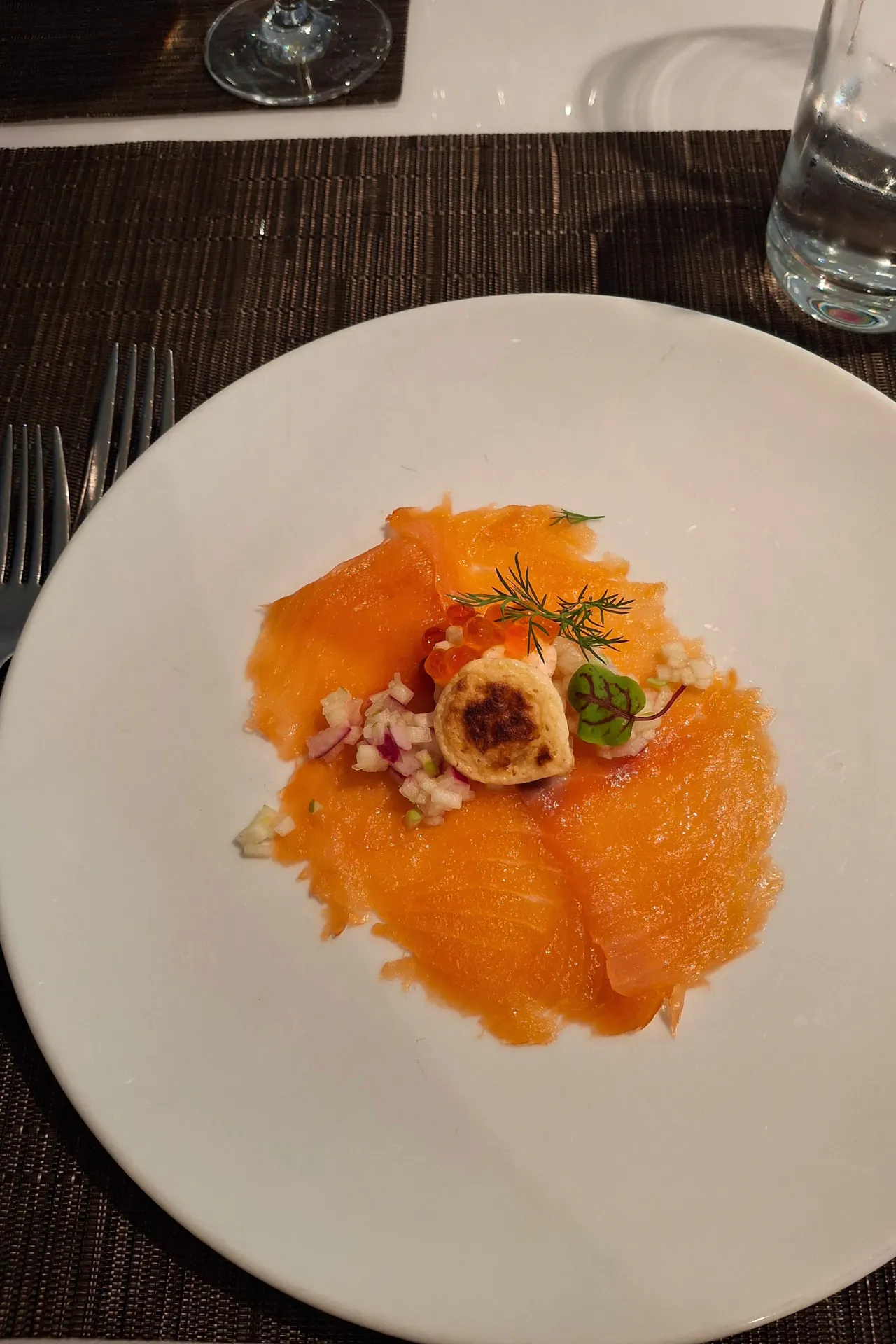 Culinair gepresenteerd diner met zalm op een rond wit bord, kleurrijk en verfijnd opgemaakt.
