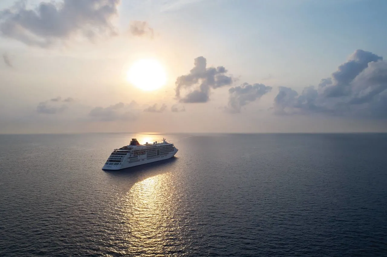 Hapag Lloyd cruiseschip vaart over open water tijdens een betoverende zonsondergang.