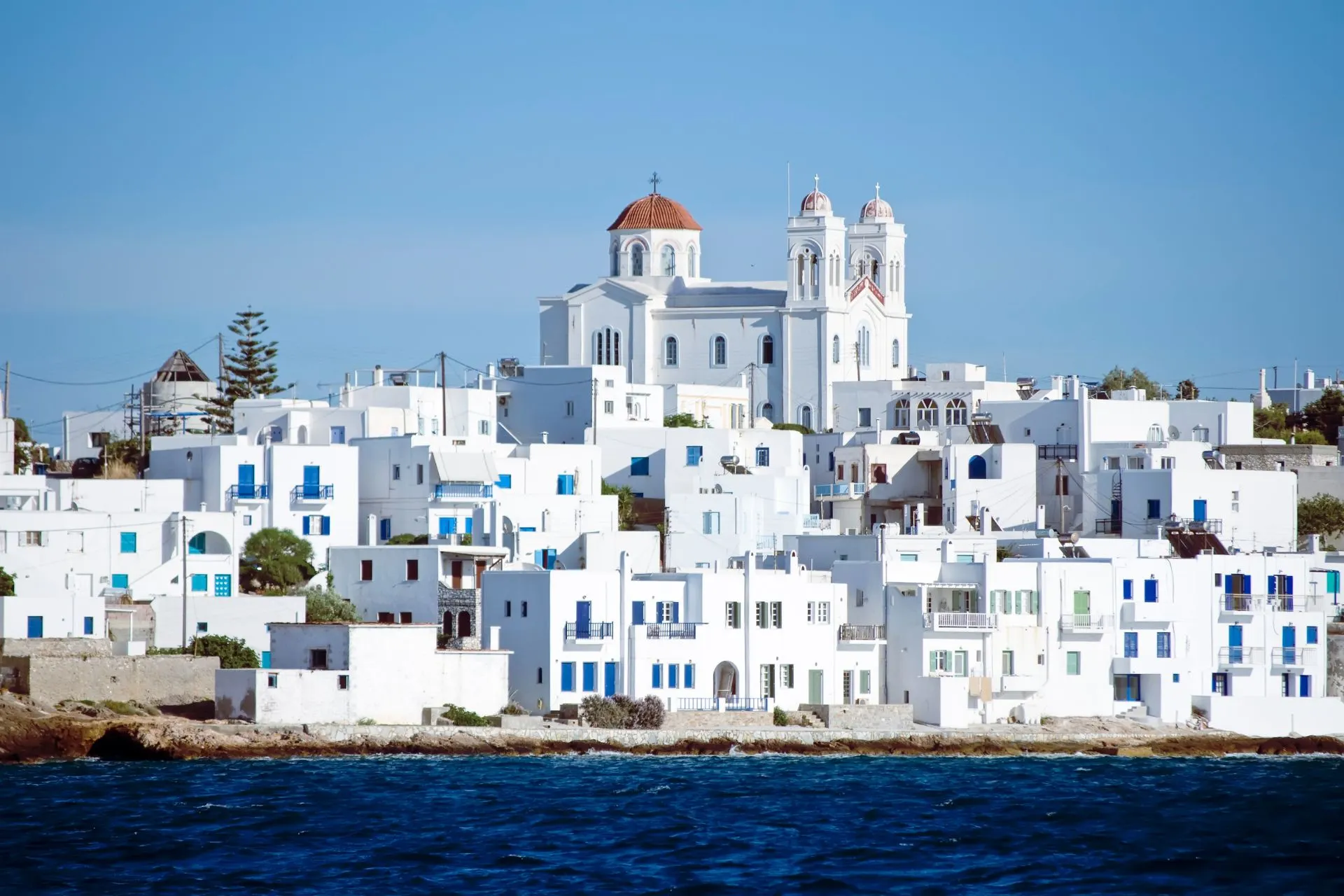 Witte huizen en een kerk aan zee op Paros, een sfeervol Grieks eiland zonder directe vlucht
