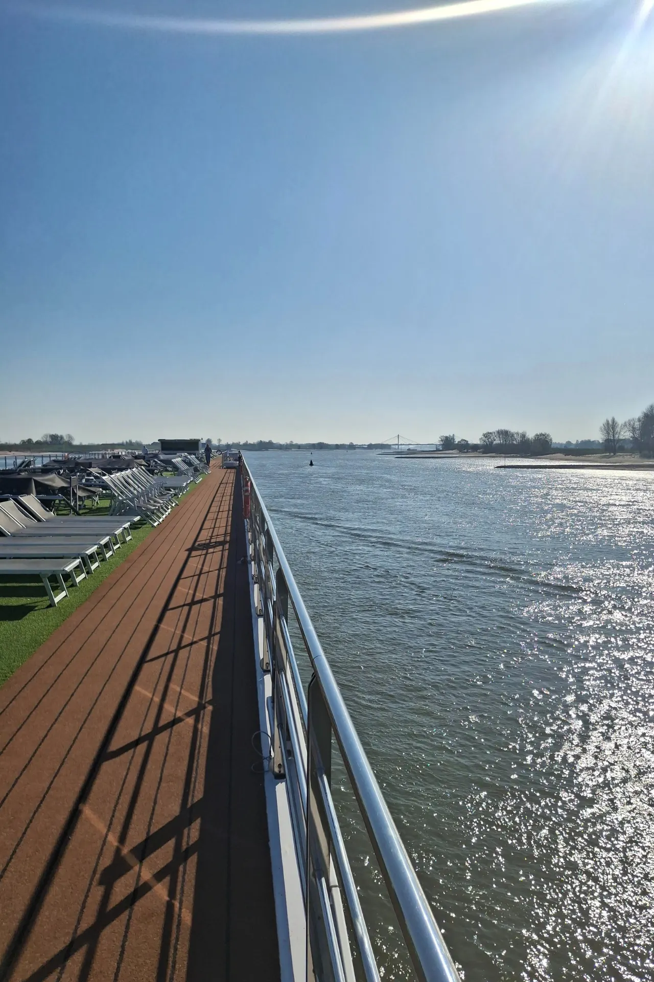 Het zonnedek van de Emerald Destiny met uitzicht op het kalme water en de omliggende natuur.