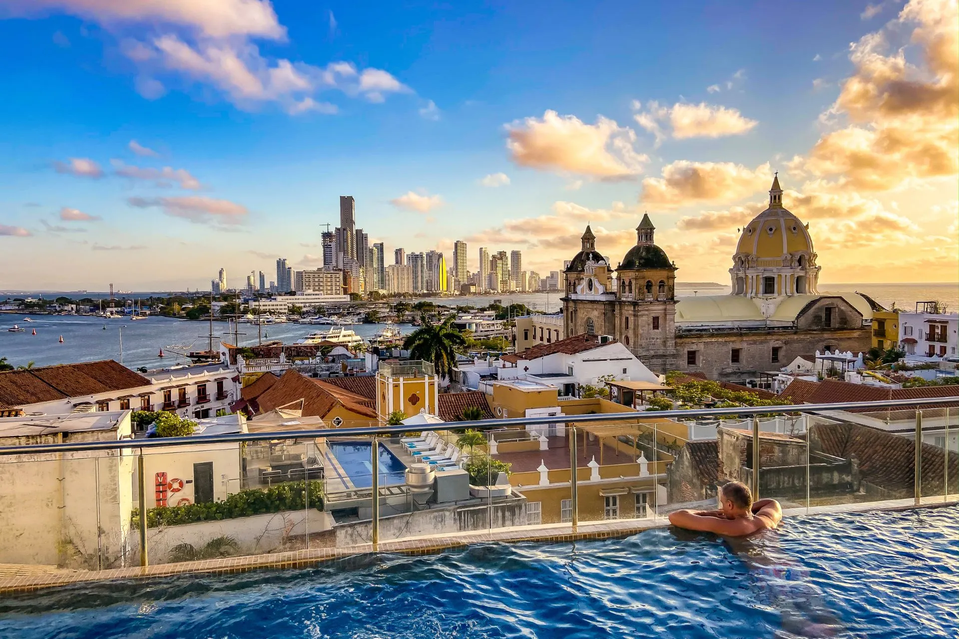 Adembenemend uitzicht op de stad Cartagena vanaf een hotelterras, met een infinitypool op de voorgrond en de kustlijn in de verte, onder een stralende zon.