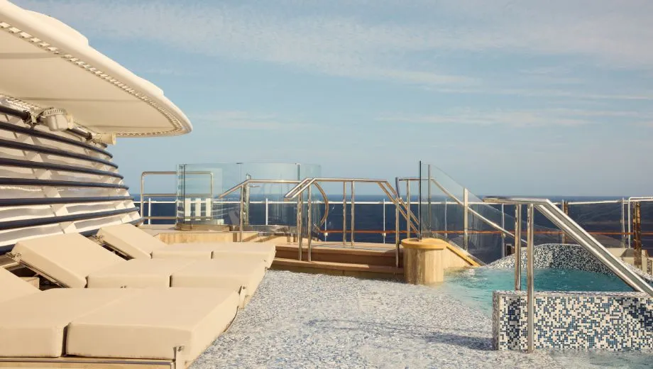 Luxe buitenzwembad en zonneterras op een Explora Cruise schip, met comfortabele ligbedden en een prachtig uitzicht op de oceaan onder een heldere blauwe lucht. Deze foto benadrukt de premium faciliteiten en ontspanningsmogelijkheden die Explora Journeys biedt voor een exclusieve cruisevakantie. Geniet van wellness, zon en rust op zee, gecombineerd met hoogwaardige service en een verfijnde sfeer, ideaal voor reizigers die op zoek zijn naar luxe en comfort tijdens hun cruise.