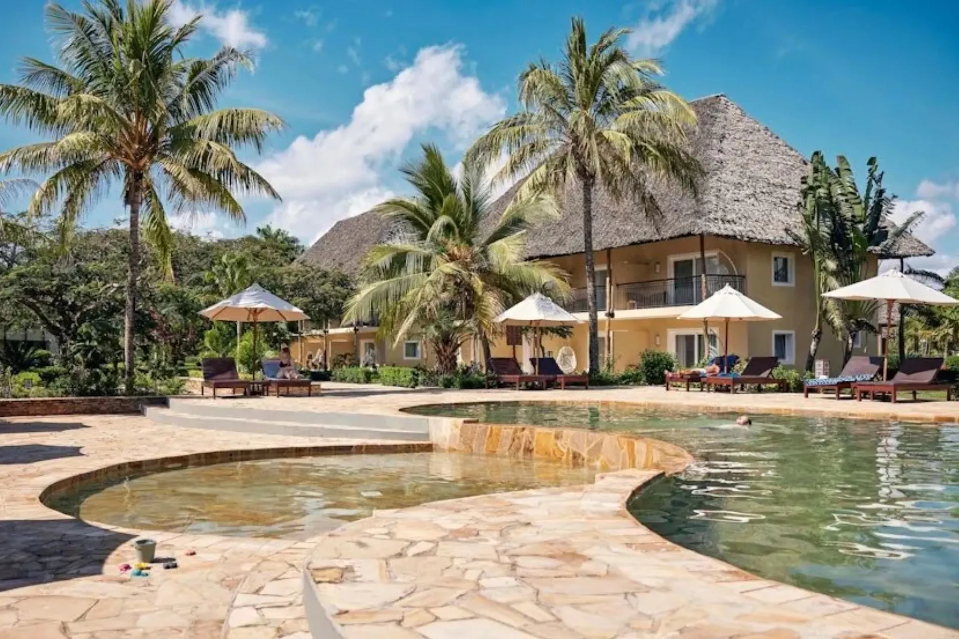 TUI BLUE Bahari Zanzibar in Pwani Mchangani met een groot zwembad, luxe ligbedden en hoge palmbomen rondom het resort. Het stijlvolle all-inclusive hotel aan de oostkust van Zanzibar combineert Afrikaanse invloeden met moderne faciliteiten en ligt direct aan het witte zandstrand van de Indische Oceaan.