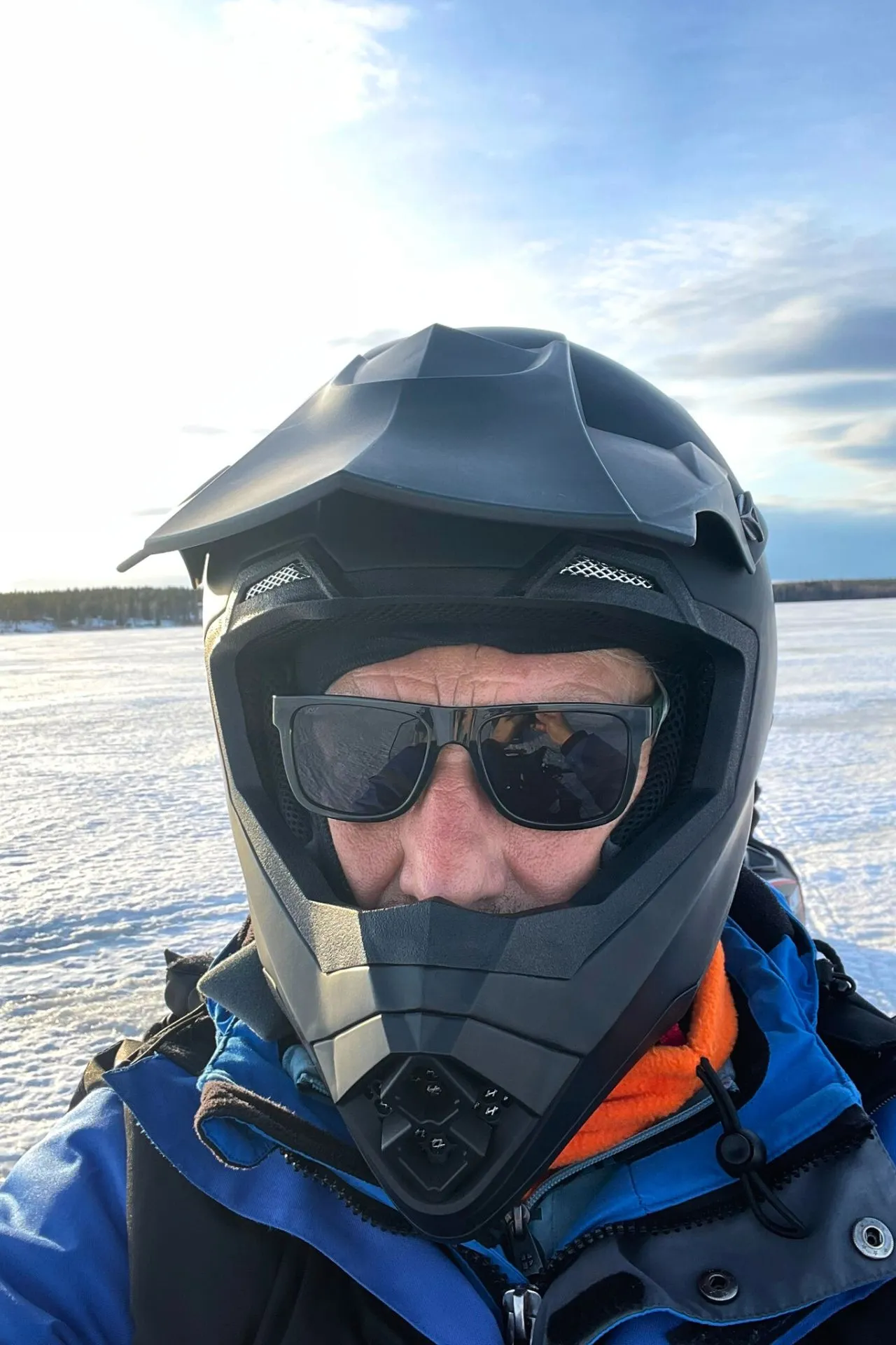 Ad, de baas van Travelcenter de Wit, maakt een selfie op een sneeuwscooter. Hij draagt een helm en een zonnebril, en geniet van het avontuur in de sneeuw.