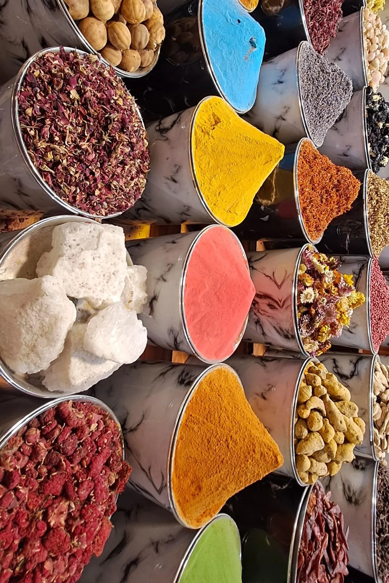 Kleurrijke specerijen en kruiden in metalen bakken op een traditionele markt in Dubai.