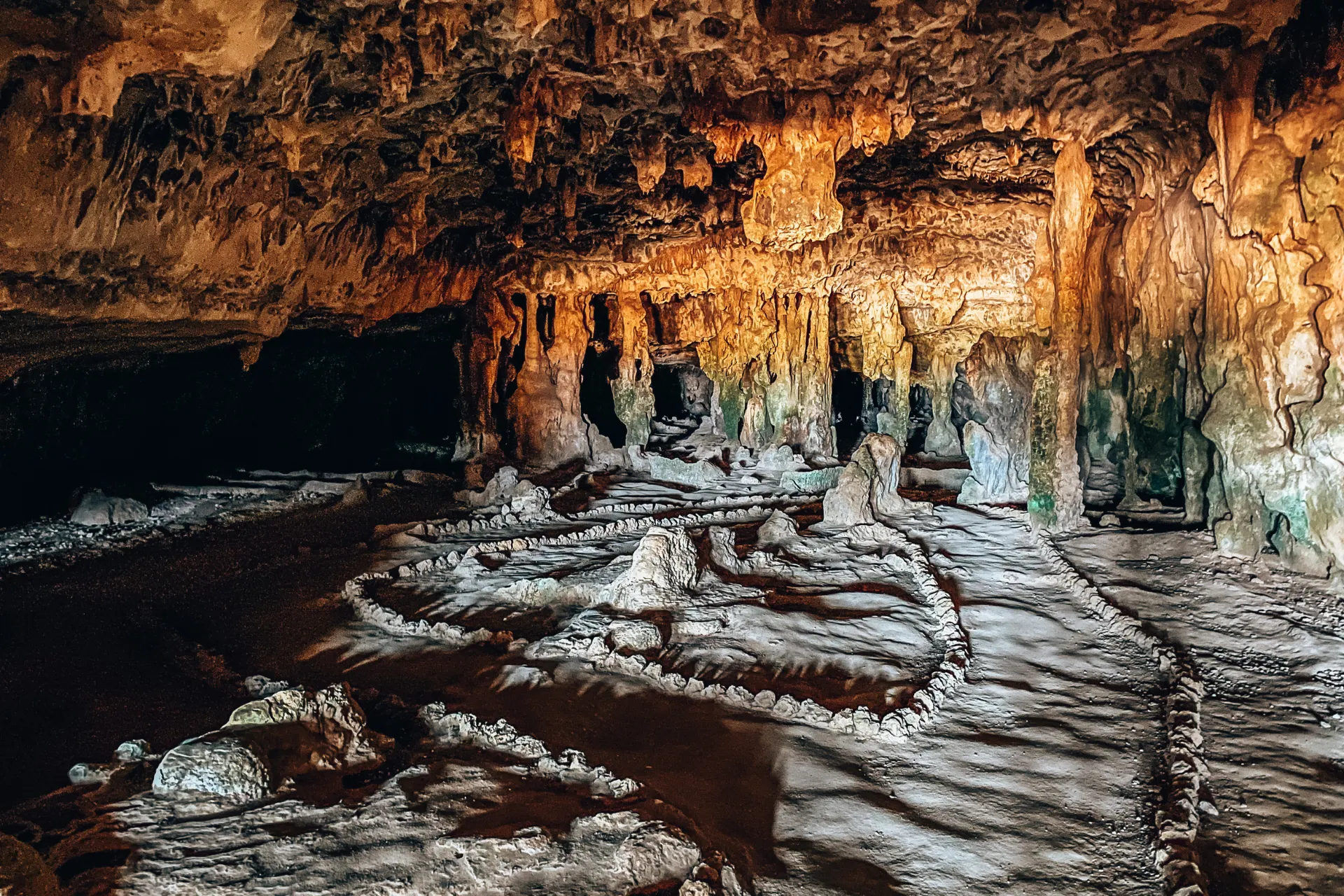 Indrukwekkende kalksteengrot met stalactieten en stalagmieten in warme aardetinten, verlicht door natuurlijk en kunstmatig licht dat de textuur van de rotsformaties benadrukt, een mysterieuze ondergrondse locatie ideaal voor avontuurlijke excursies en natuurontdekking