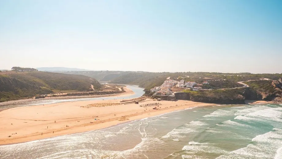 "Adembenemend uitzicht op de kust van Alentejo, Portugal, met brede zandstranden, een riviermonding en de Atlantische Oceaan. Het landschap toont golvende heuvels, een charmant dorp op de kliffen en helderblauw water. Ideaal voor een zomervakantie in Portugal, geniet van zon, zee, natuur en rust. Ontdek verborgen stranden, wandelroutes en authentieke kustplaatsen in het prachtige Alentejo-gebied."