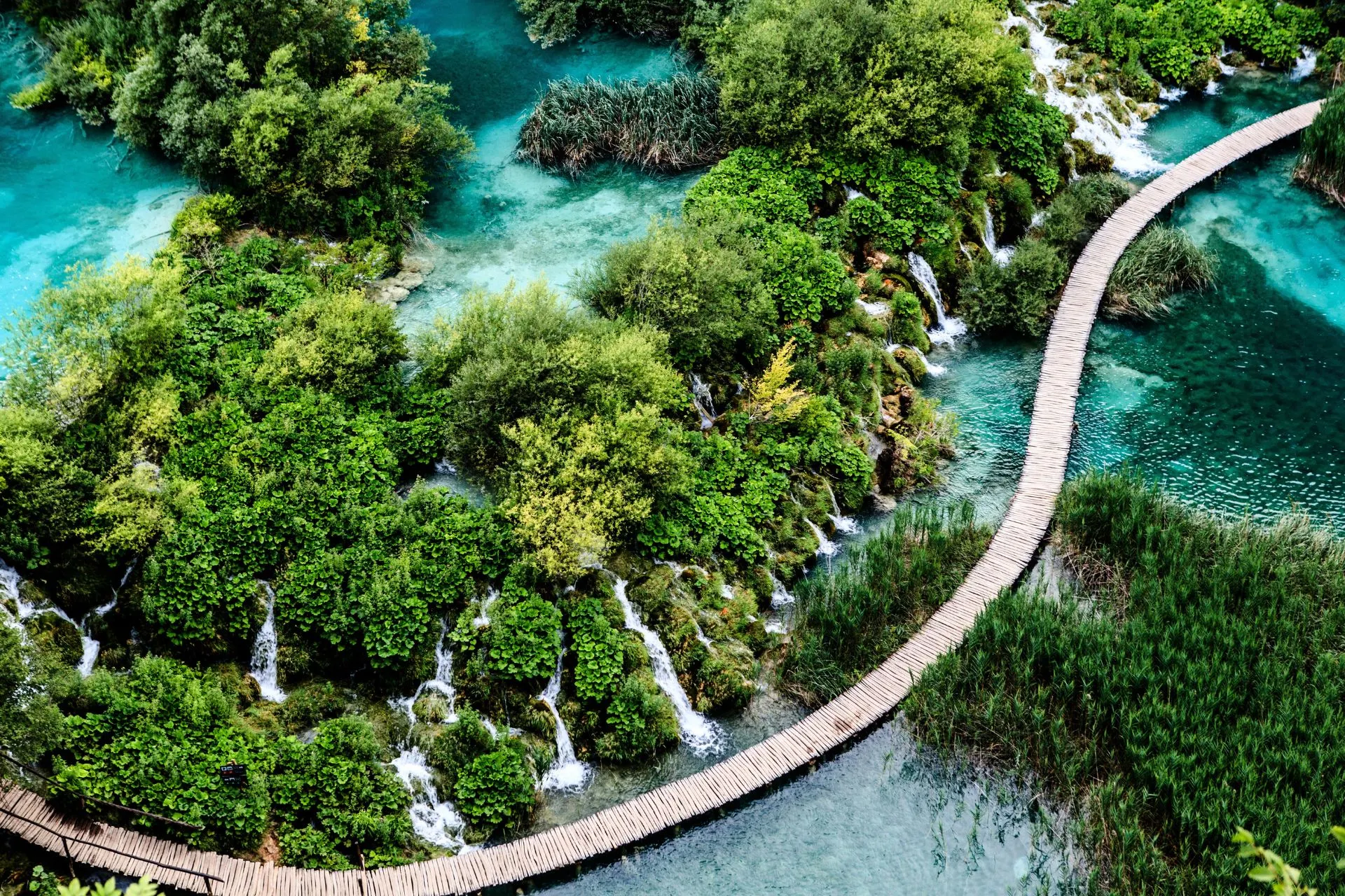 Groene omgeving in een nationaal park in Kroatië met een houten wandelbrug over helder water.