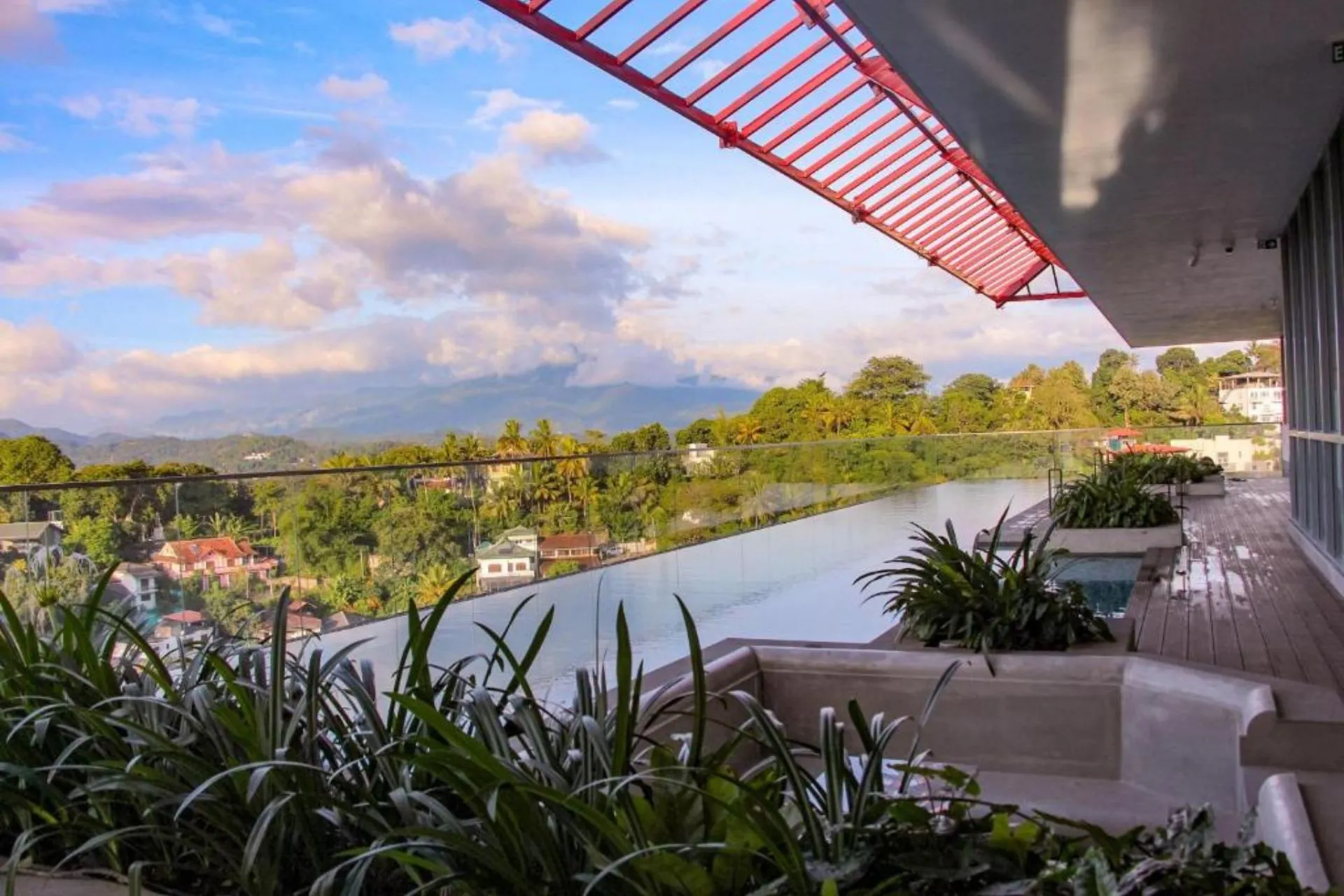 Infinity zwembad op het dakterras van Kandy Myst by Cinnamon met uitzicht over de groene heuvels en stad Kandy, met moderne zitgedeeltes en plantenbakken langs de rand.