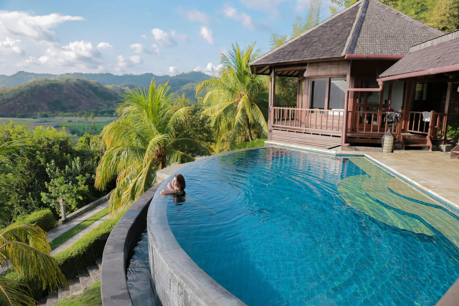 Luxe infinity pool met uitzicht op tropische heuvels en palmbomen in Bali. Deze plek is een paradijs voor wellness reizen en een yoga retreat. Combineer ontspanning met een digital detox vakantie en laat je inspireren door de rust van een offline vakantie. Ideaal voor slow travel, waarbij je bewust geniet van de natuur en de serene sfeer van deze exotische bestemming.

