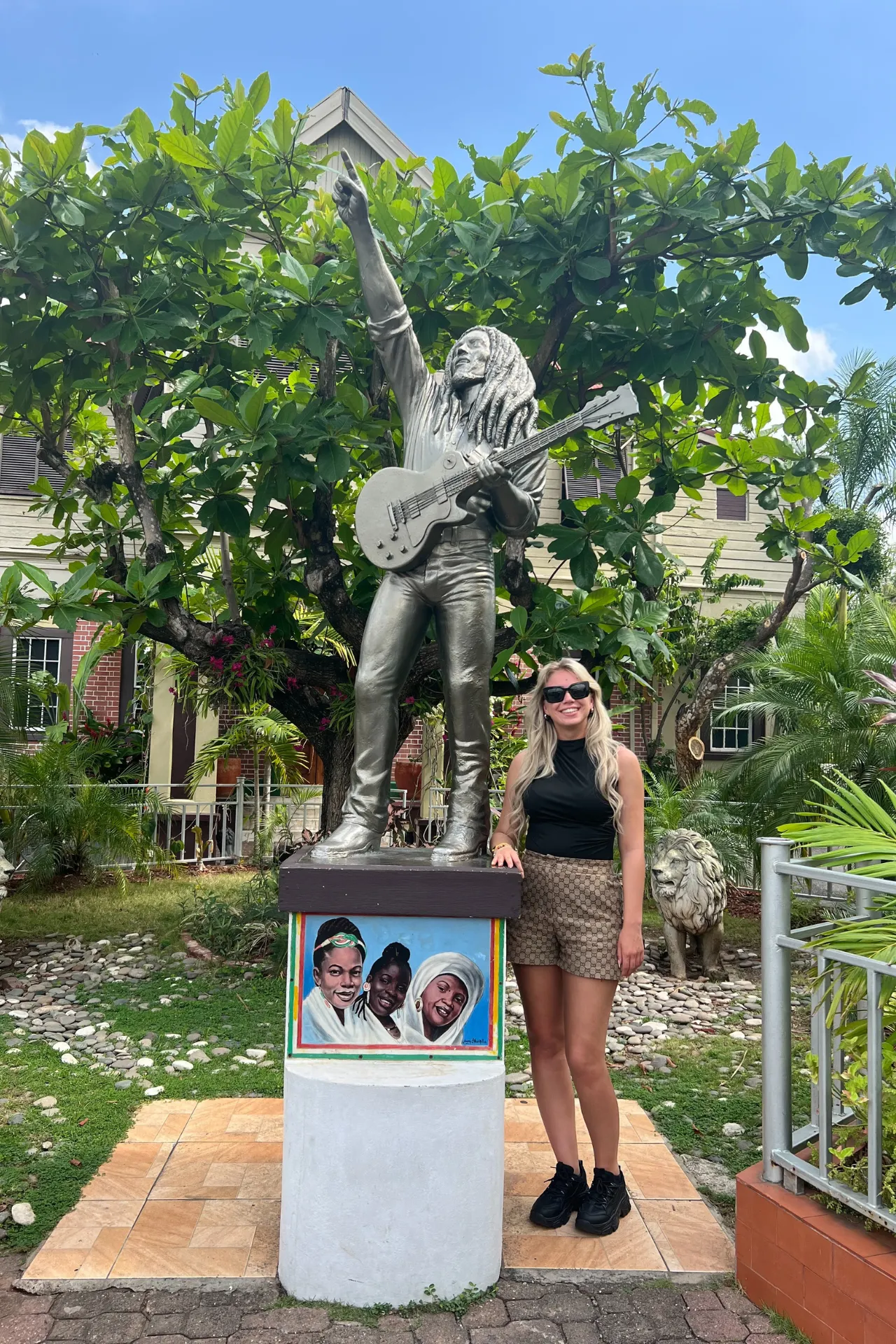 Cultureel moment op Jamaica: een blonde dame bij het beroemde Bob Marley beeld, symbool van reggae en eilandgeschiedenis.