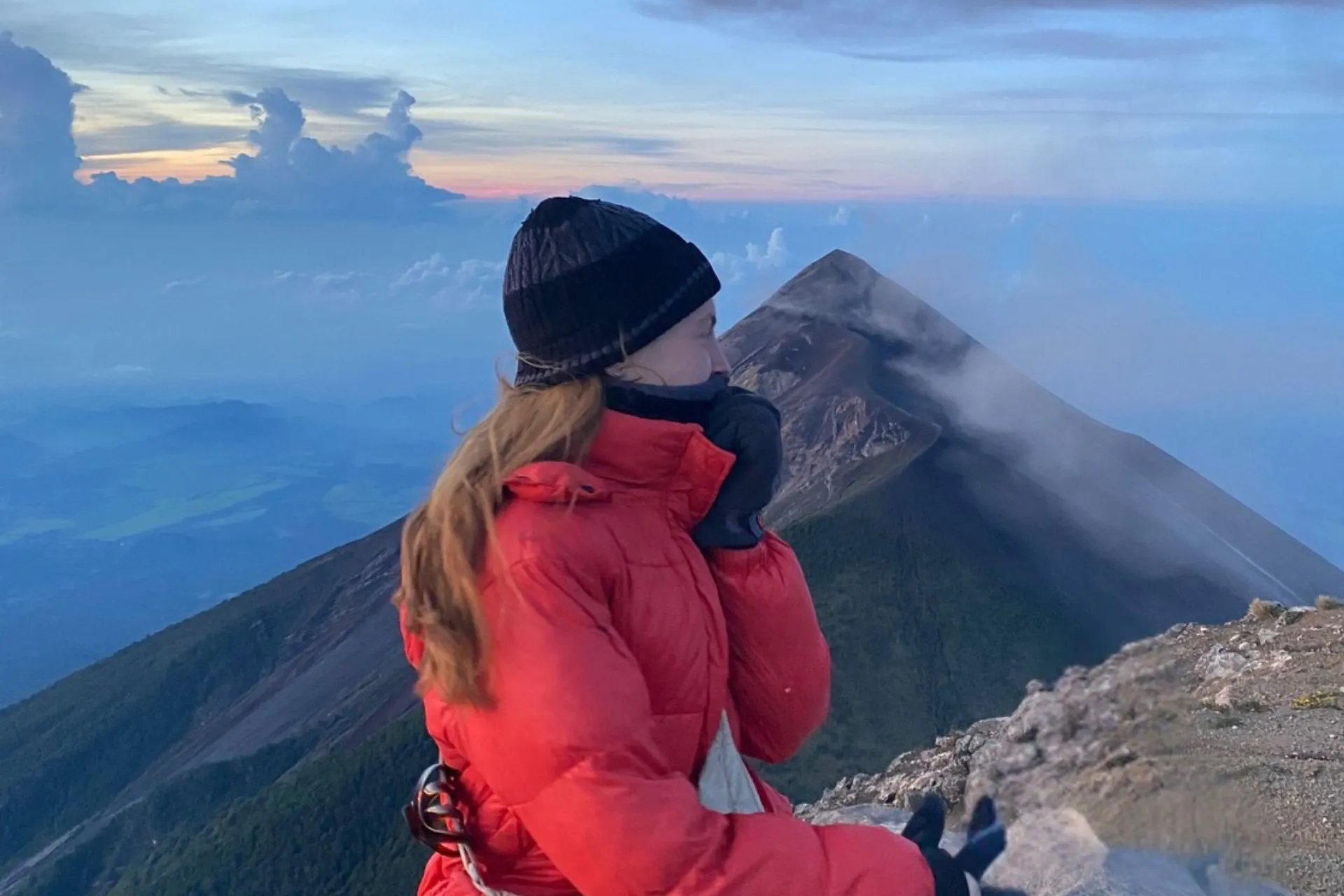 Uitzicht vanaf de Acatenango‑vulkaan tijdens zonsopkomst, met de Volcán de Fuego op de achtergrond en het berglandschap van Guatemala.