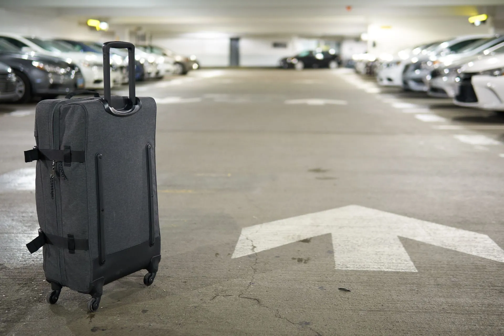 Overdekt parkeren bij Düsseldorf vliegveld – een reiziger met koffer in de parkeergarage bij Düsseldorf luchthaven. Perfecte optie voor lang parkeren Düsseldorf Airport of dichtbij parkeren bij terminal Düsseldorf luchthaven.