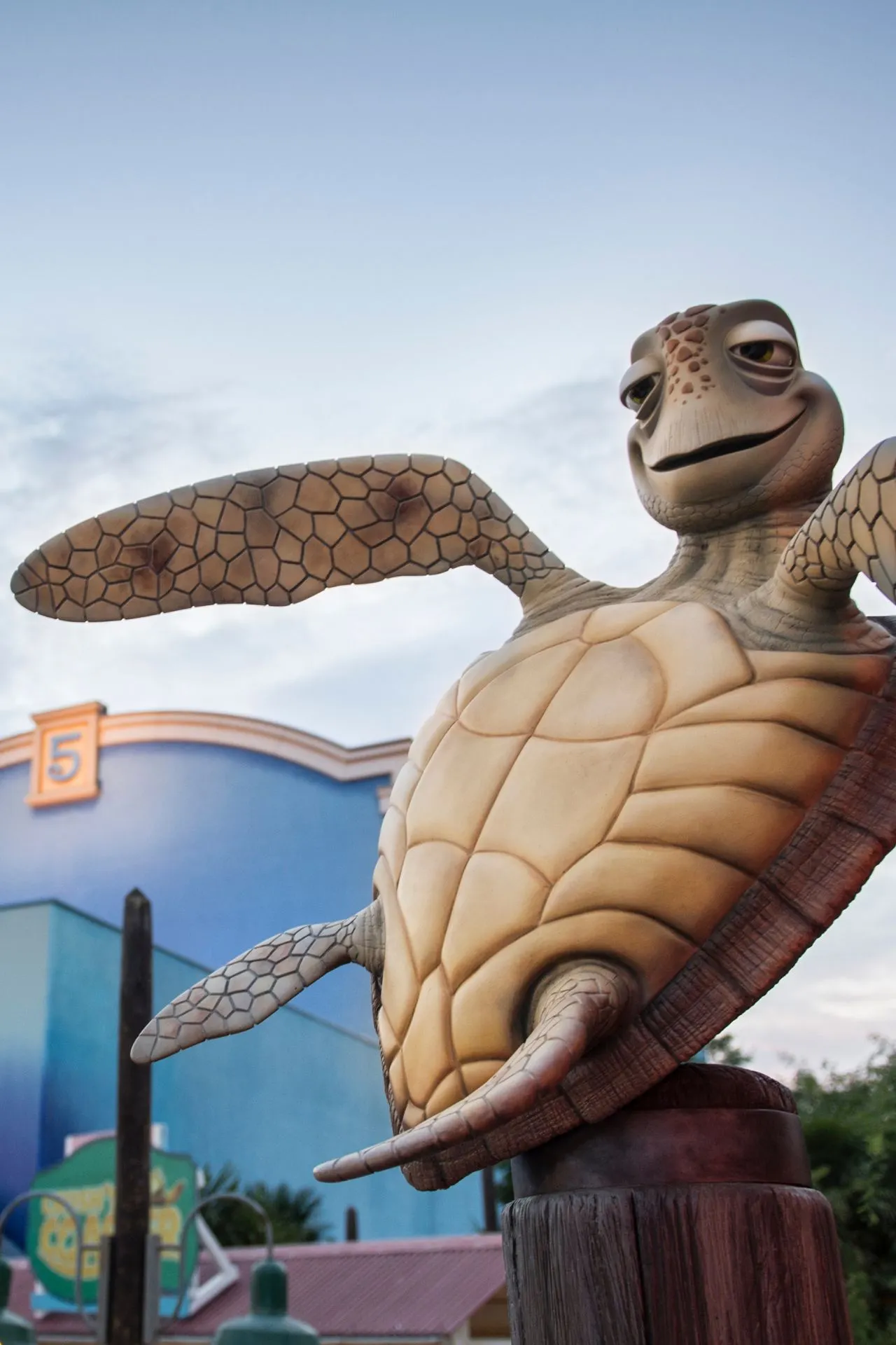 Beeld van Crush, de zeeschildpad uit Finding Nemo, bij Walt Disney Studios Park in Disneyland Parijs, met een blauwe gevel en nummer 5 op de achtergrond onder een licht bewolkte hemel.