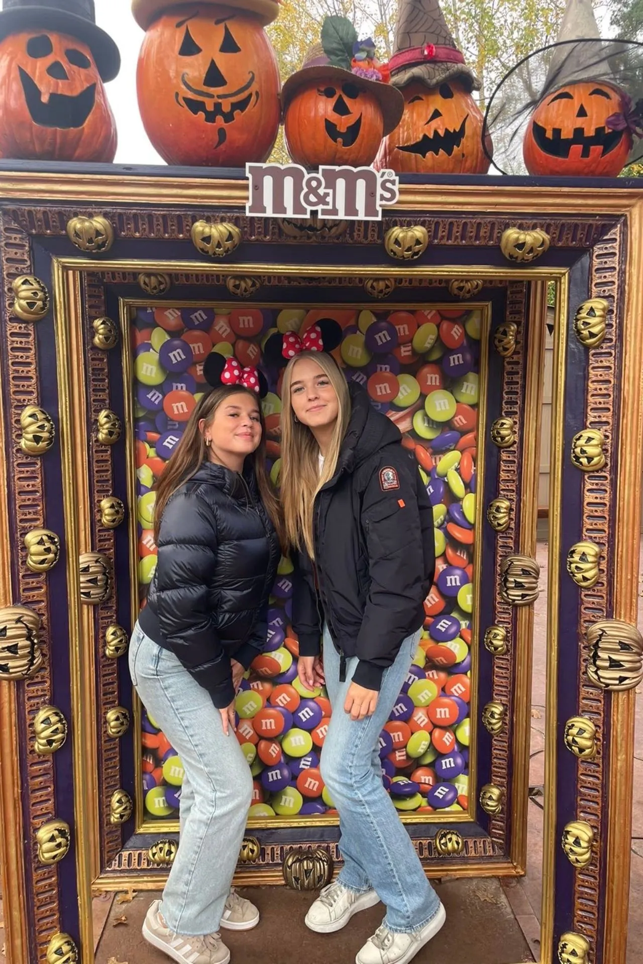 Halloween-decoratie bij Disneyland Parijs met een M&M's fotoframe omringd door pompoenen met uitgesneden gezichten en gouden details.