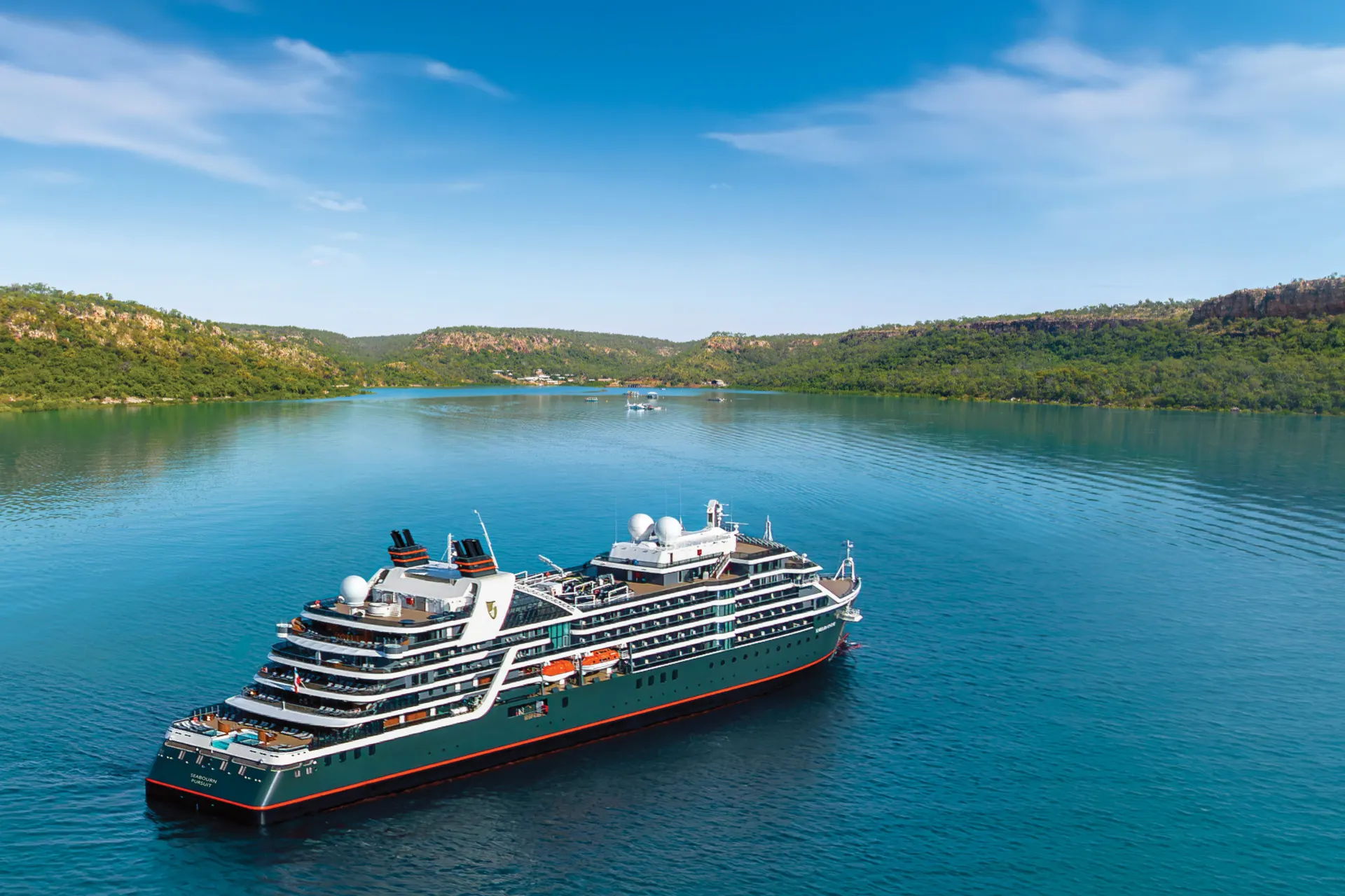 Seabourn Kimberley vaart over een groot meer in Australië omringd door groen