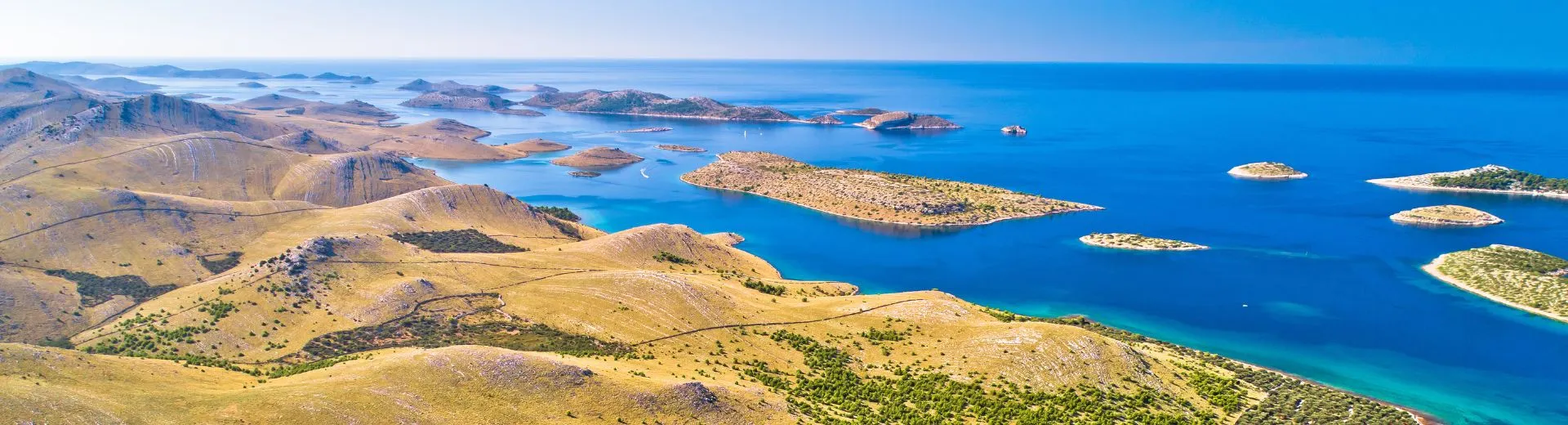 Uitzicht over ruige Griekse eilanden zonder directe vlucht met helderblauwe zee en ongerepte natuur