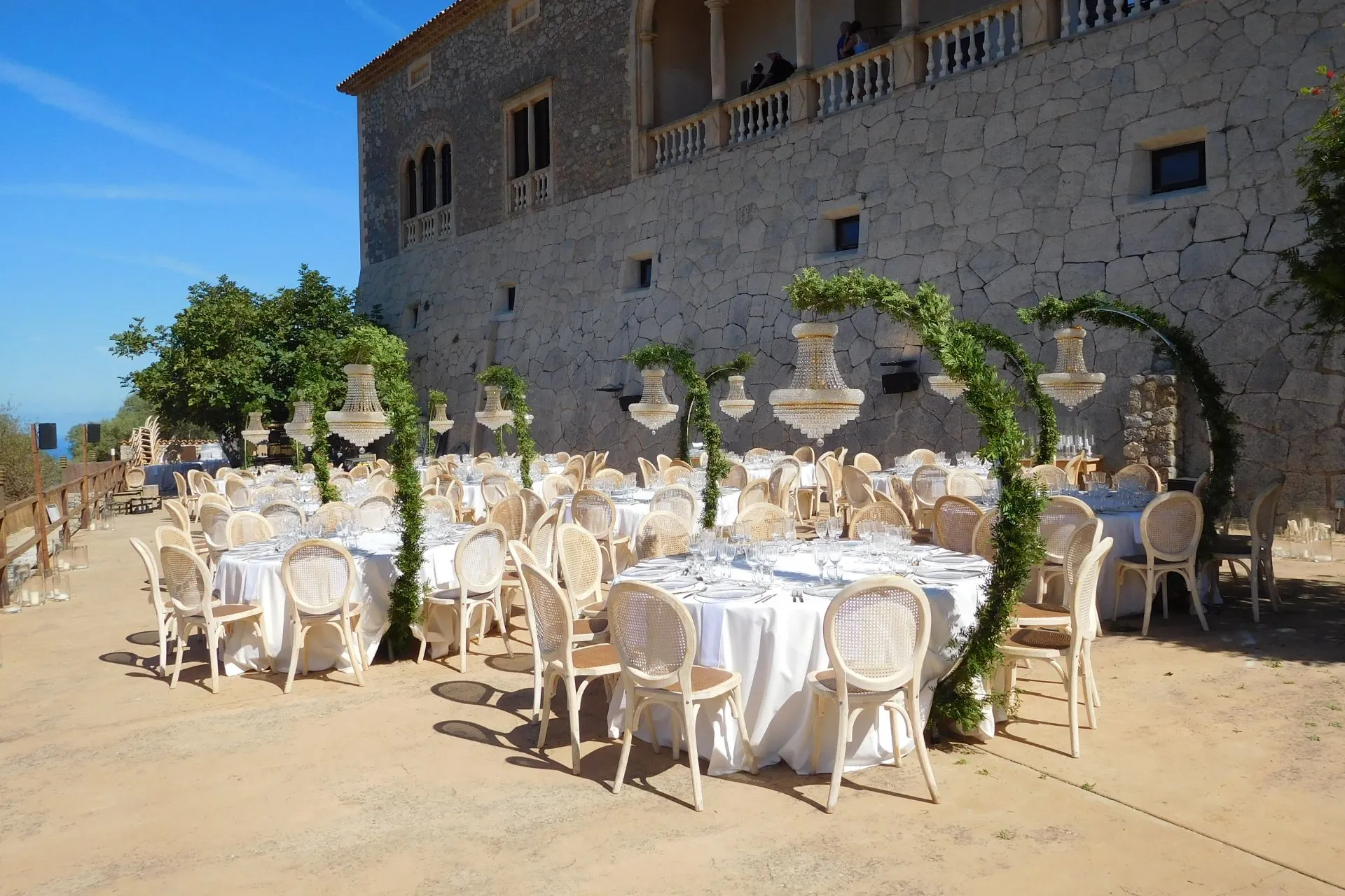 Romantische trouwlocatie bij Son Morroig op Mallorca met prachtig gedekte ronde tafels, elegante stoelen en groene decoratie onder een stralende blauwe lucht. Deze historische plek aan de kust van de Serra de Tramuntana is ideaal voor bruiloften en evenementen met uitzicht op zee. Populaire bestemming voor luxe feesten en bijzondere momenten op Mallorca.
