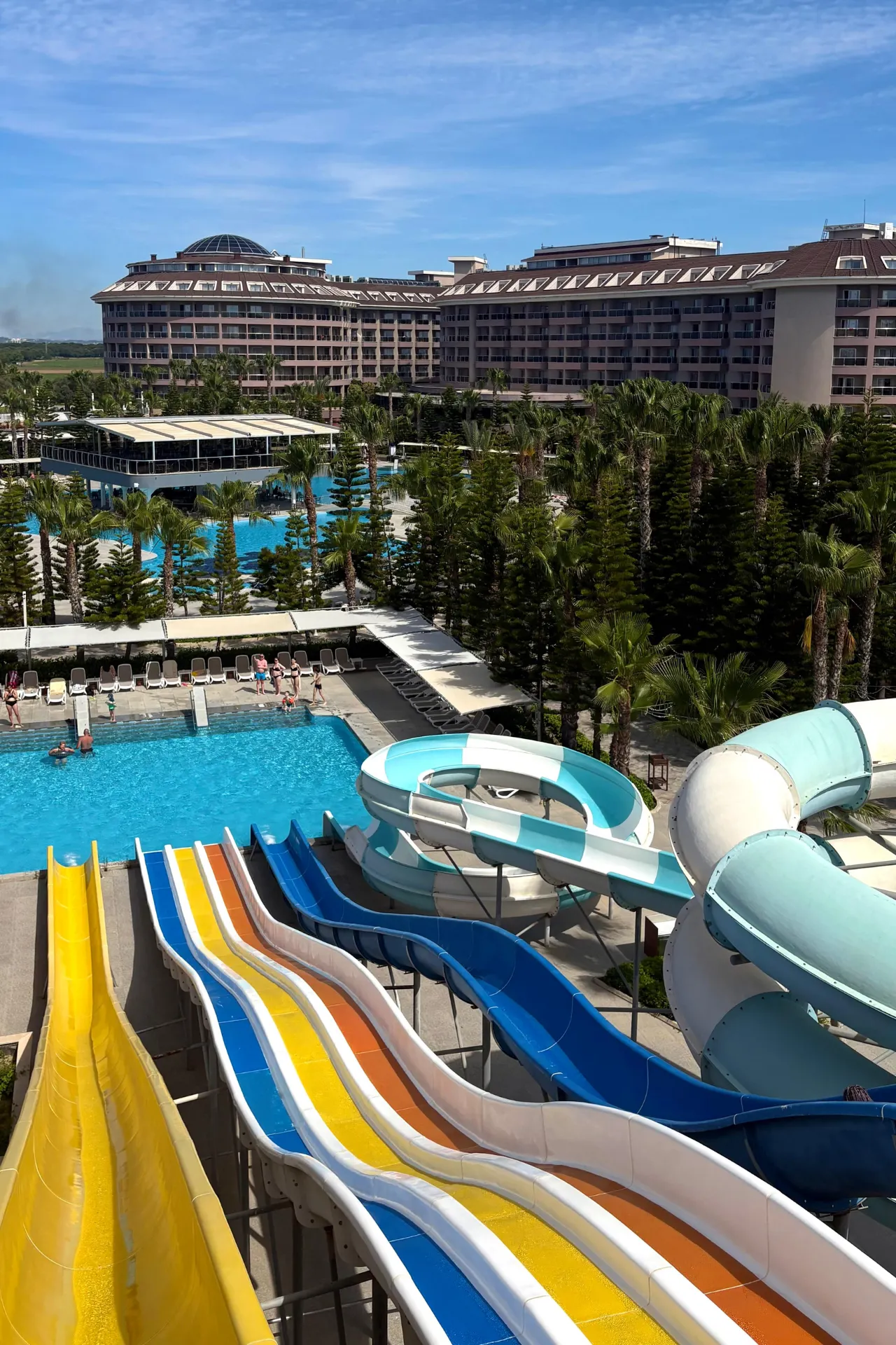 Waterpark van Sunmelia Beach Resort met kleurrijke glijbanen, zwembaden en tropische palmbomen. Vanuit dit overzicht is goed te zien dat het resort uitgebreide faciliteiten biedt voor gezinnen en liefhebbers van waterpret tijdens een all inclusive vakantie aan de Turkse Rivièra.