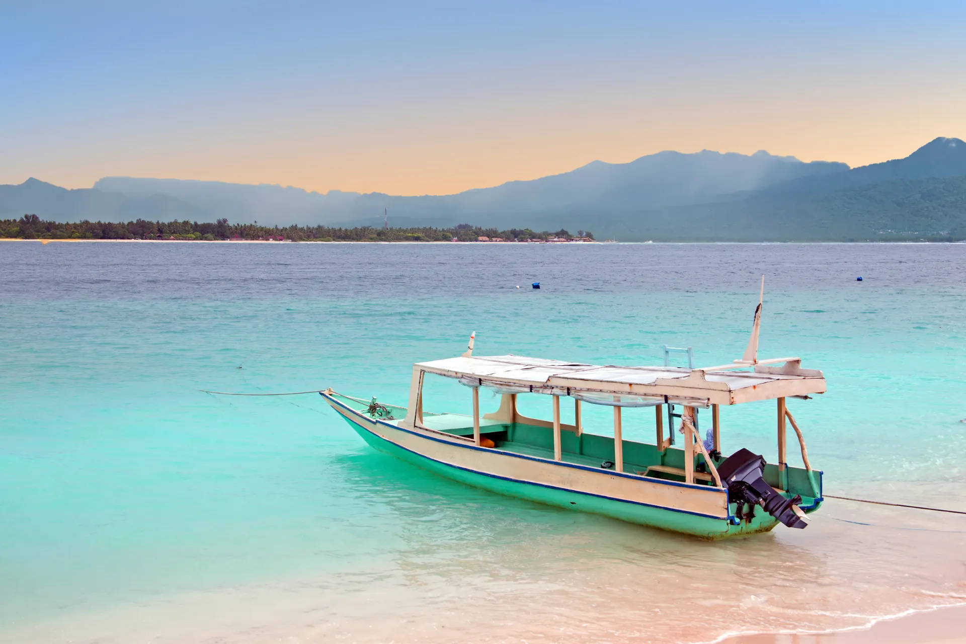 Helder blauw water bij Kepulauan Riau Indonesië met een bootje en een prachtige zonsondergang aan de horizon.