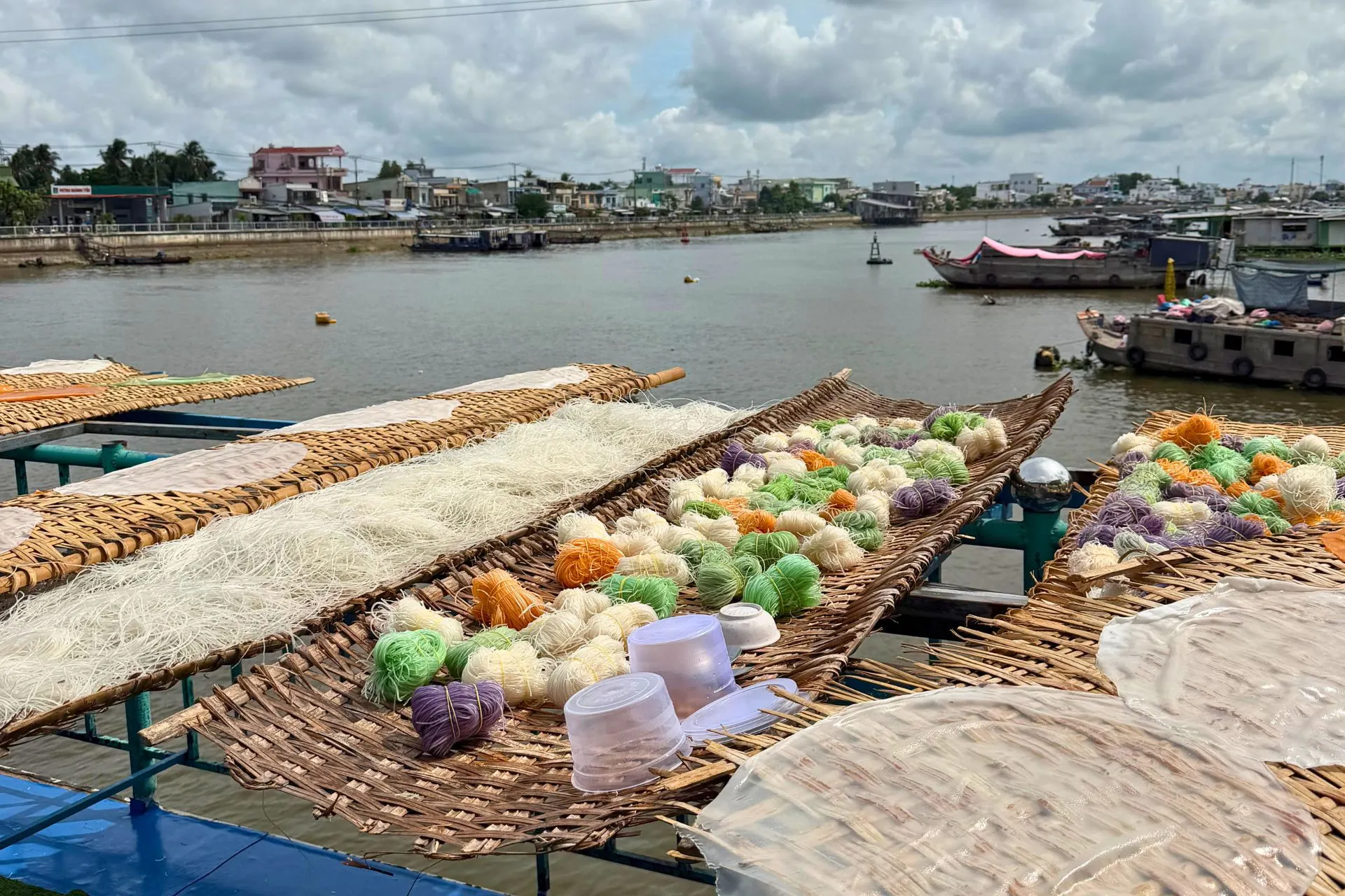 Traditioneel geproduceerde rijstnoedels en rijstpapier drogen in de zon langs een rivier in de Mekong Delta, Vietnam. Tijdens een bezoek aan een lokale werkplaats ontdek je hoe deze belangrijke ingrediënten van de Vietnamese keuken volgens ambachtelijke methoden worden gemaakt.