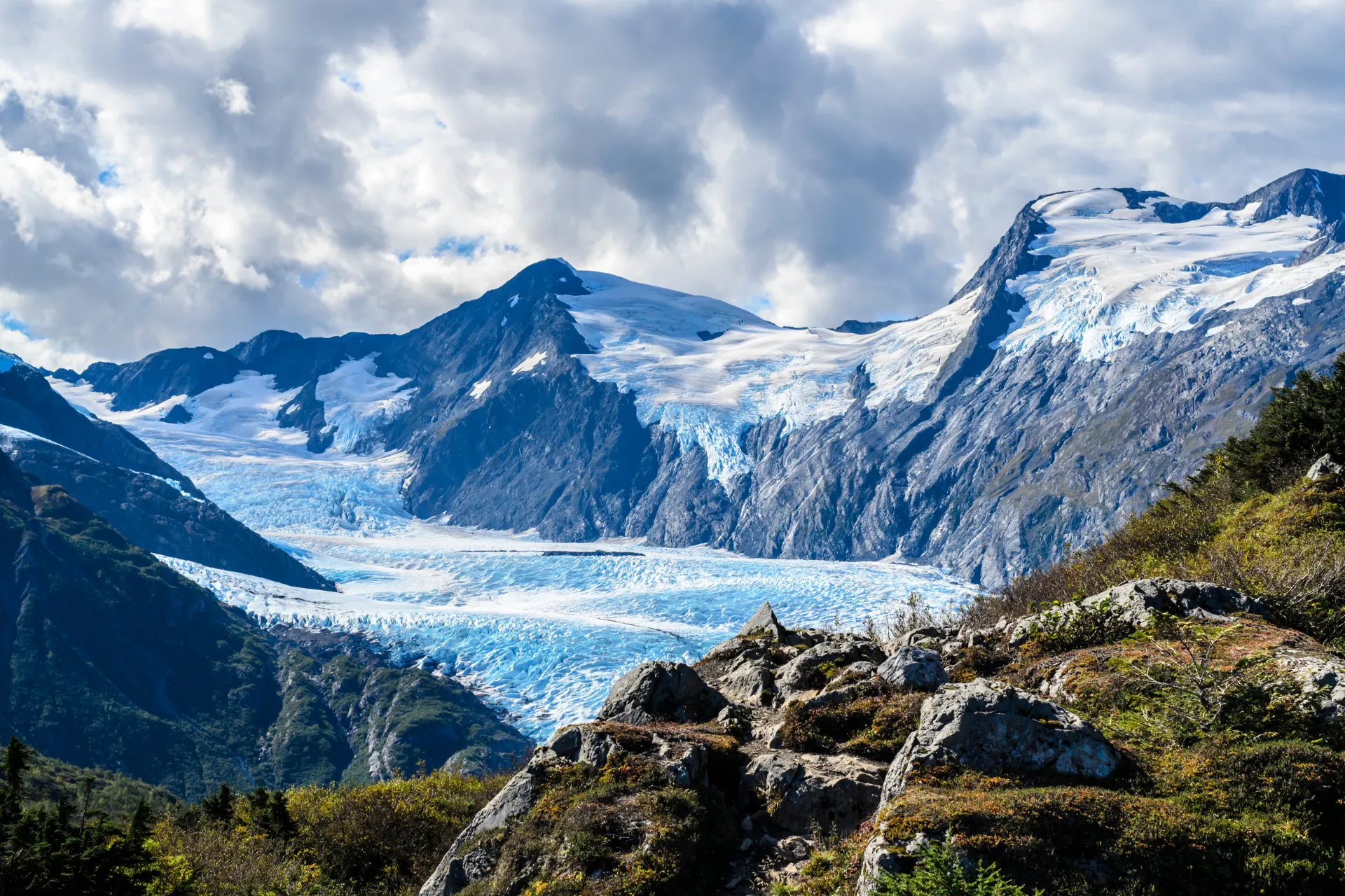 Uitzicht op het ruige landschap van Alaska met met sneeuw bedekte bergtoppen, groene hellingen en rotsformaties