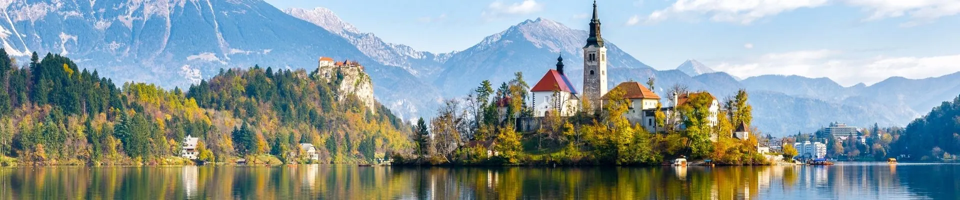Het Meer van Bled in Slovenië met het iconische eiland en kerkje, omringd door bergen en groene natuur.
