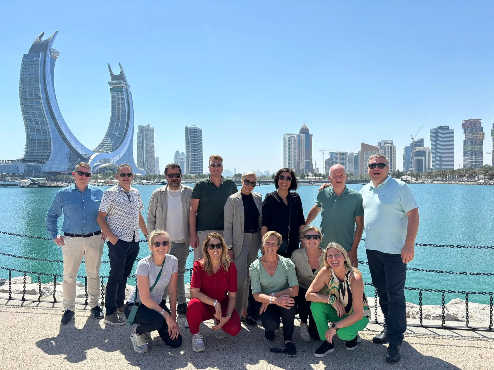 Groepsfoto tijdens onze studiereis Qatar - Doha met op de achtergrond een deel van de prachtige skyline met onder andere het iconische Fairmont & Raffles hotel