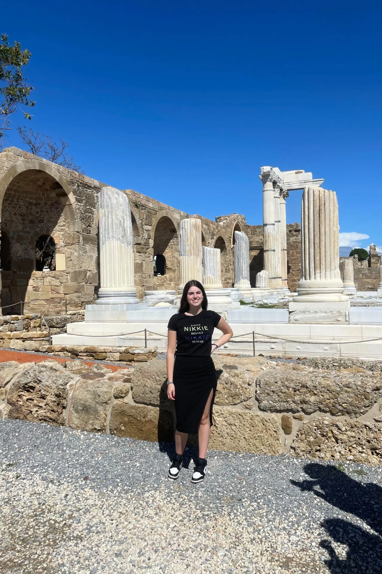 Dame met donker haar poseert bij de oude ruïnes van de Tempel van Apollo in Side, Antalya, Turkije