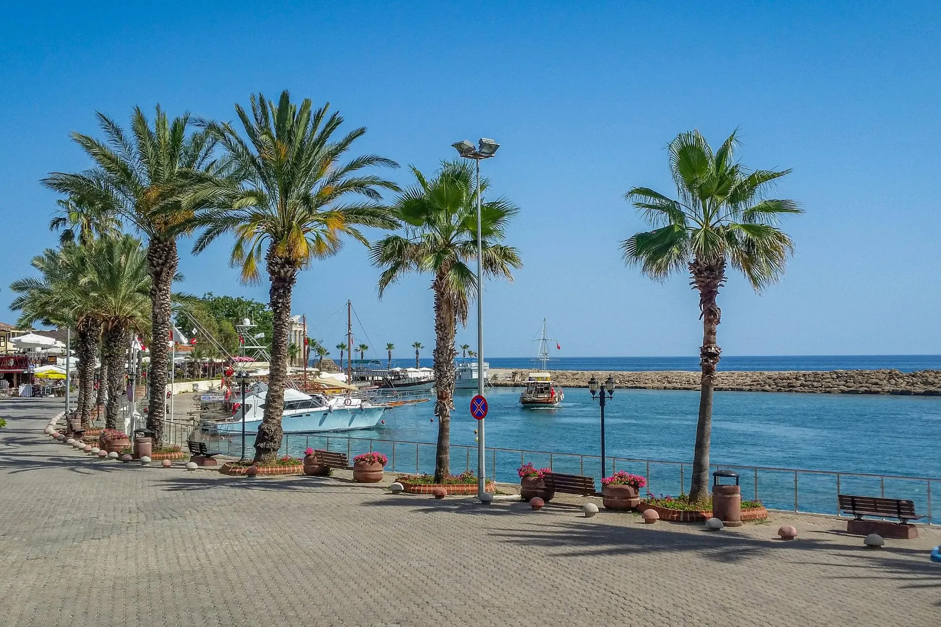 De sfeervolle haven van Side in Turkije met palmbomen, aanlegplaatsen voor excursieboten en uitzicht op de Middellandse Zee. Langs de boulevard vind je restaurants, terrasjes en winkels. De haven is een populaire bezienswaardigheid en vormt het ideale startpunt voor een bezoek aan het historische centrum van Side.
